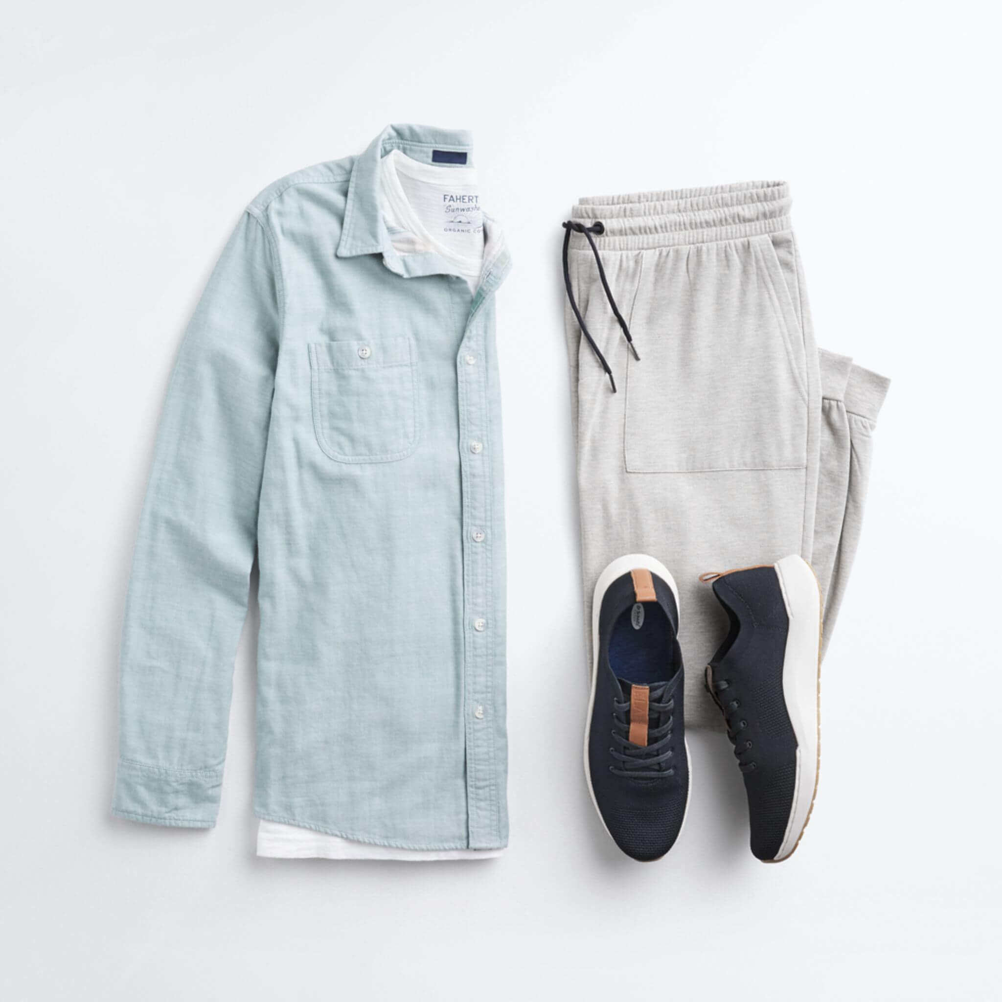 Stitch Fix Men’s outfit laydown featuring a light green button-down shirt over a white crewneck t-shirt, next to grey joggers and black sneakers. 