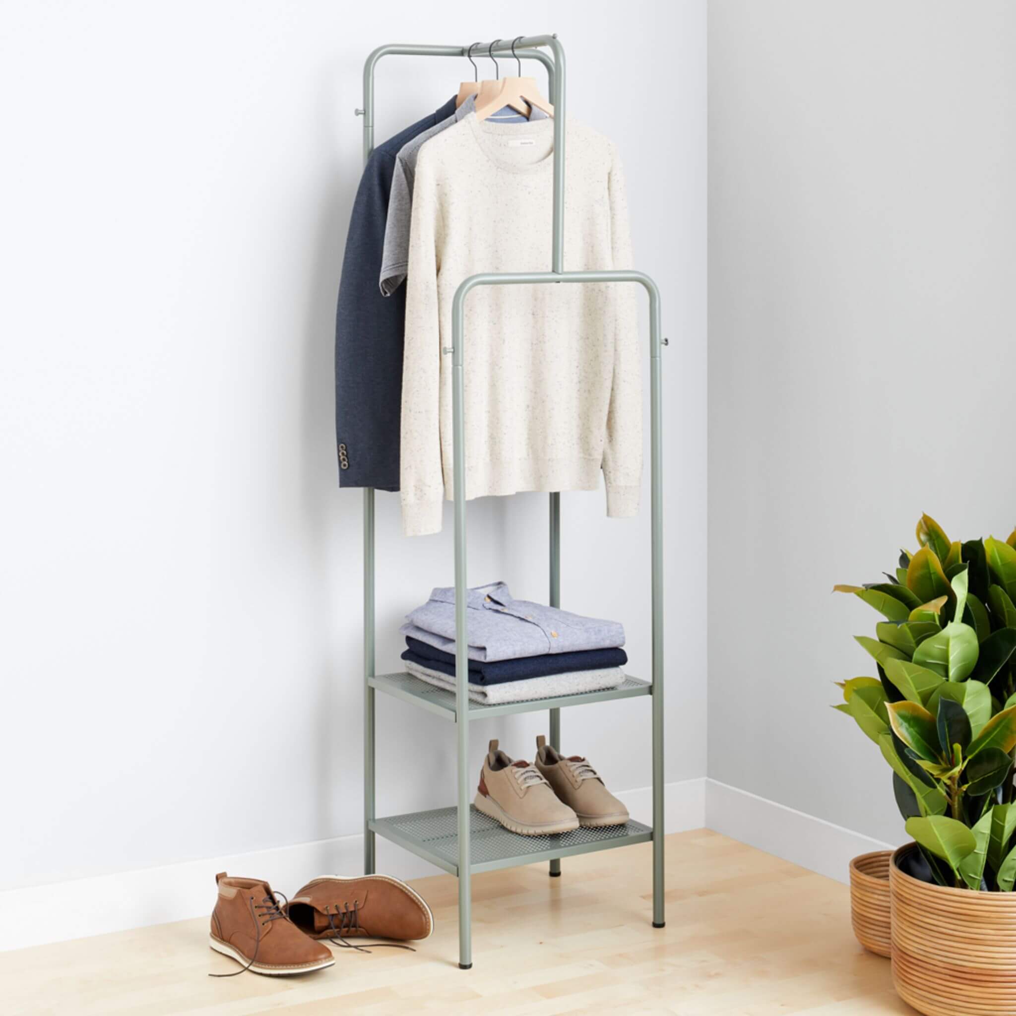 Stitch Fix Men’s cream crewneck pullover, grey polo and navy blazer hanging on grey rack, with light button-down shirts folded and tan leather sneakers on grey shelves, next to brown chukkas on the floor.