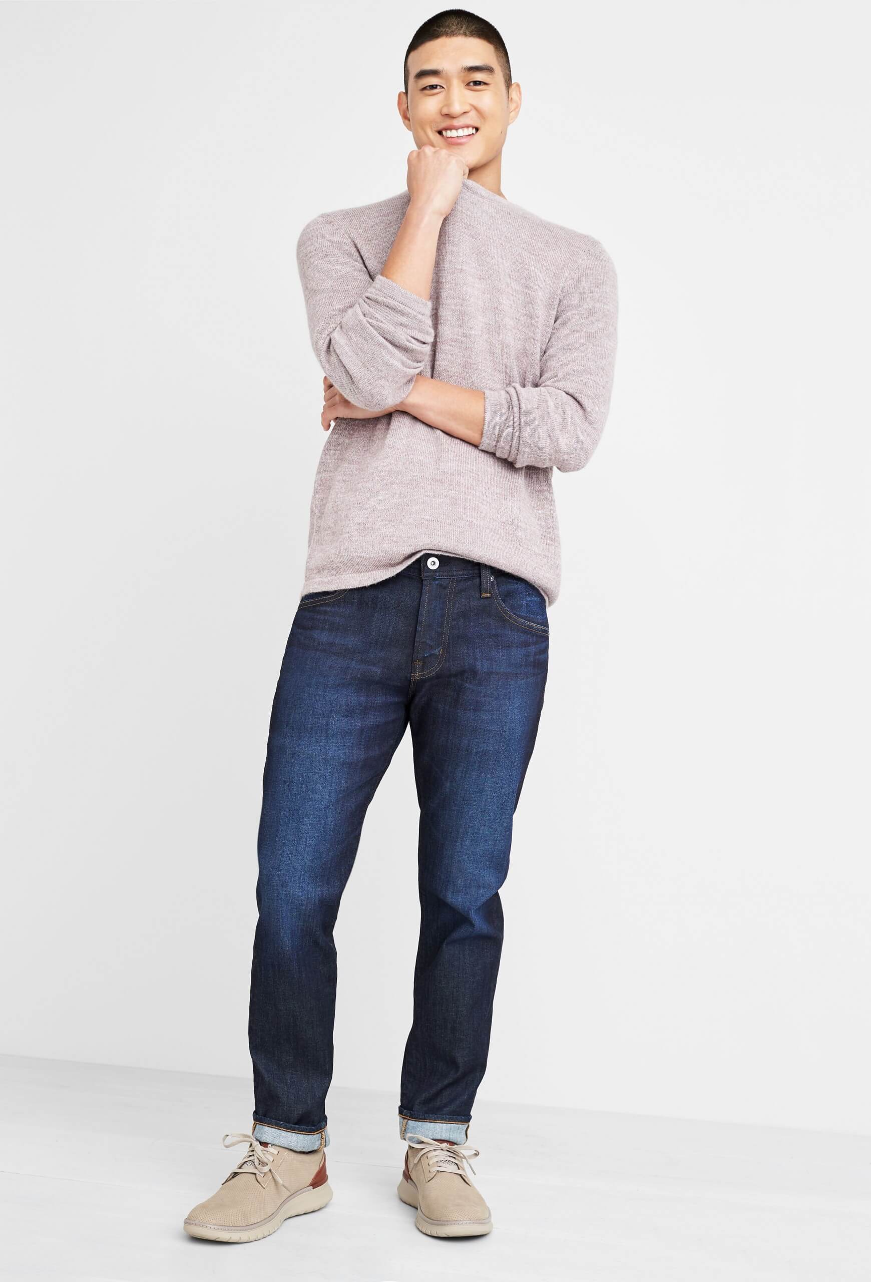 Stitch Fix Men’s model wearing dark wash jeans, beige crewneck sweater and beige leather sneakers. 