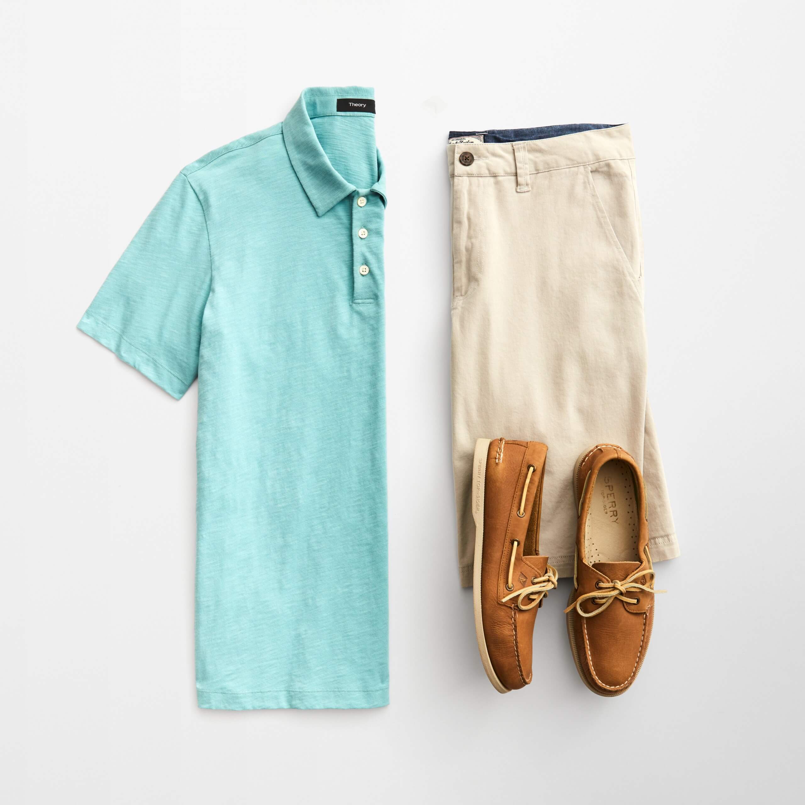 Stitch Fix Men’s outfit laydown featuring a light blue polo, khaki shorts and brown boat shoes.