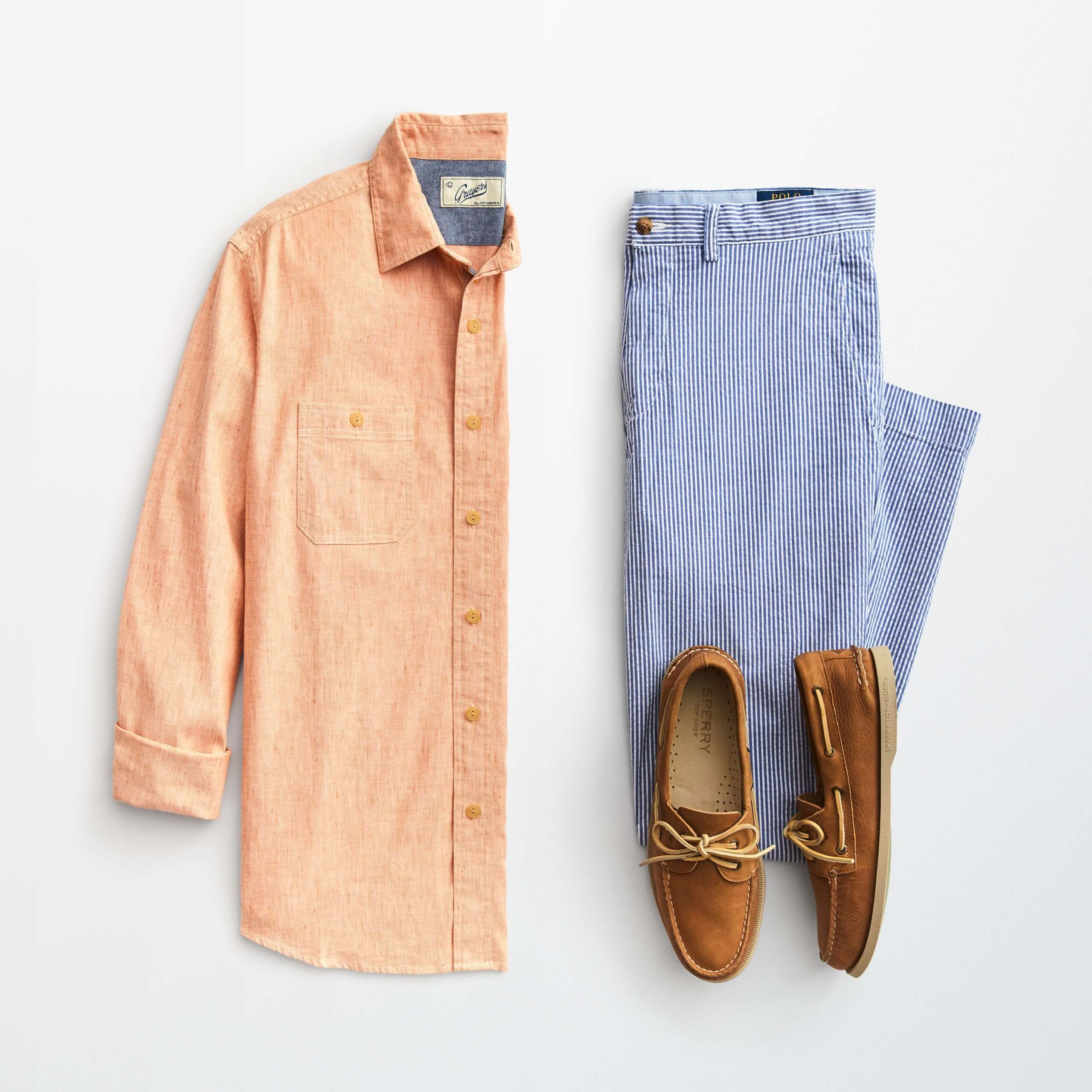 Stitch Fix Men’s outfit laydown featuring an orange button-down shirt, blue striped chinos and brown boat shoes.