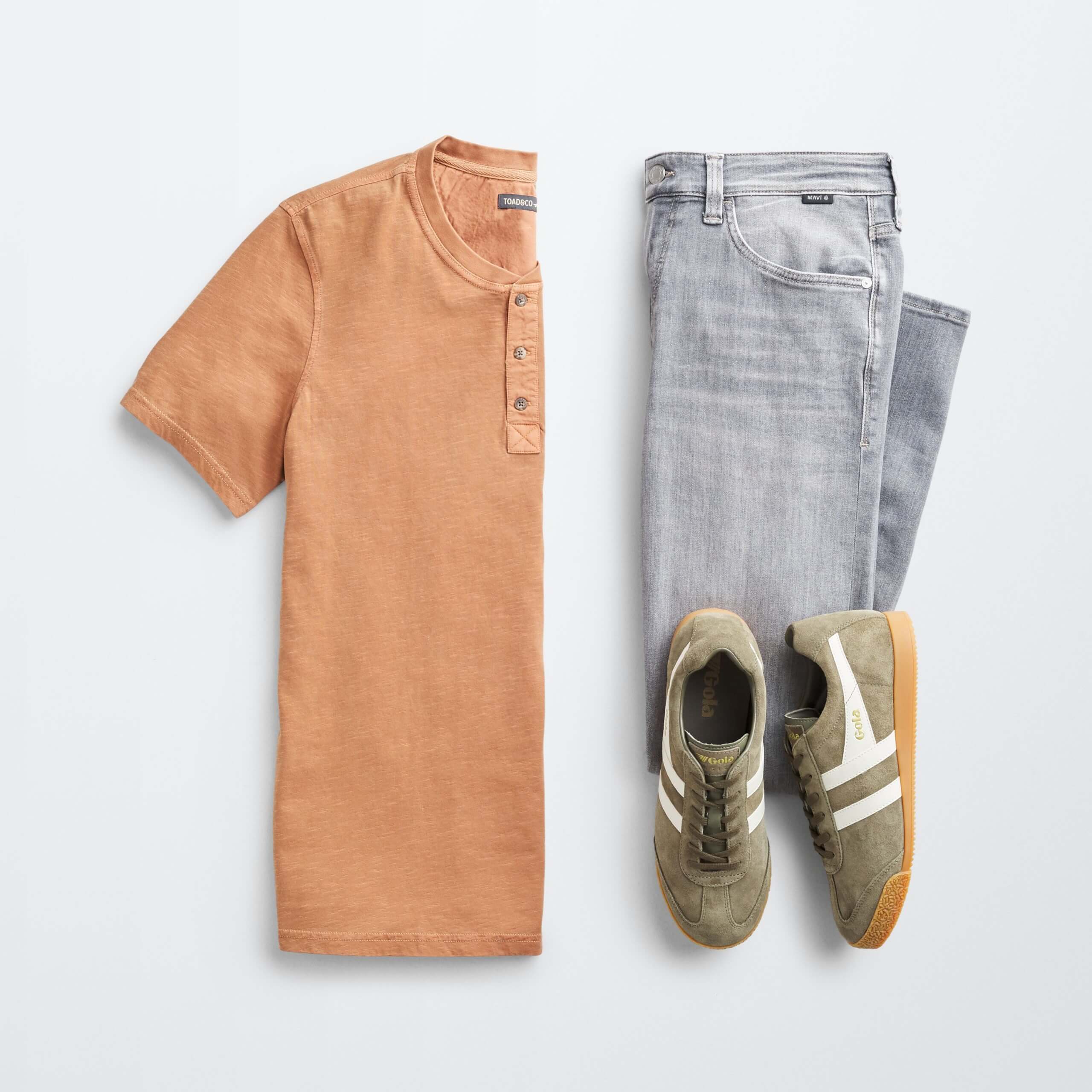 Stitch Fix Men’s outfit laydown featuring orange henley shirt, grey jeans and olive green sneakers. 