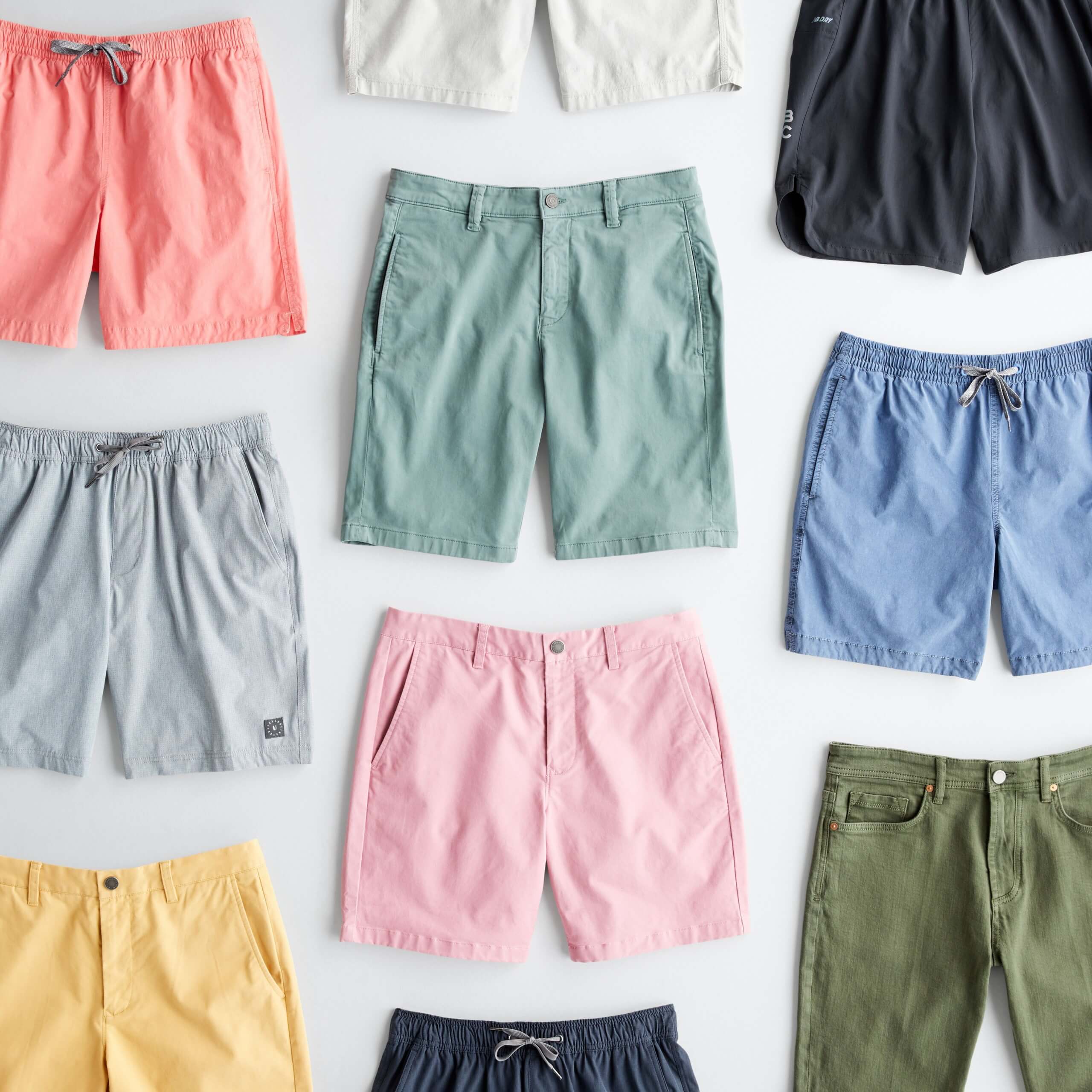 Stitch Fix Men’s outfit laydown featuring multiple pairs of shorts in coral, white, green, black, blue, pink, yellow and grey. 