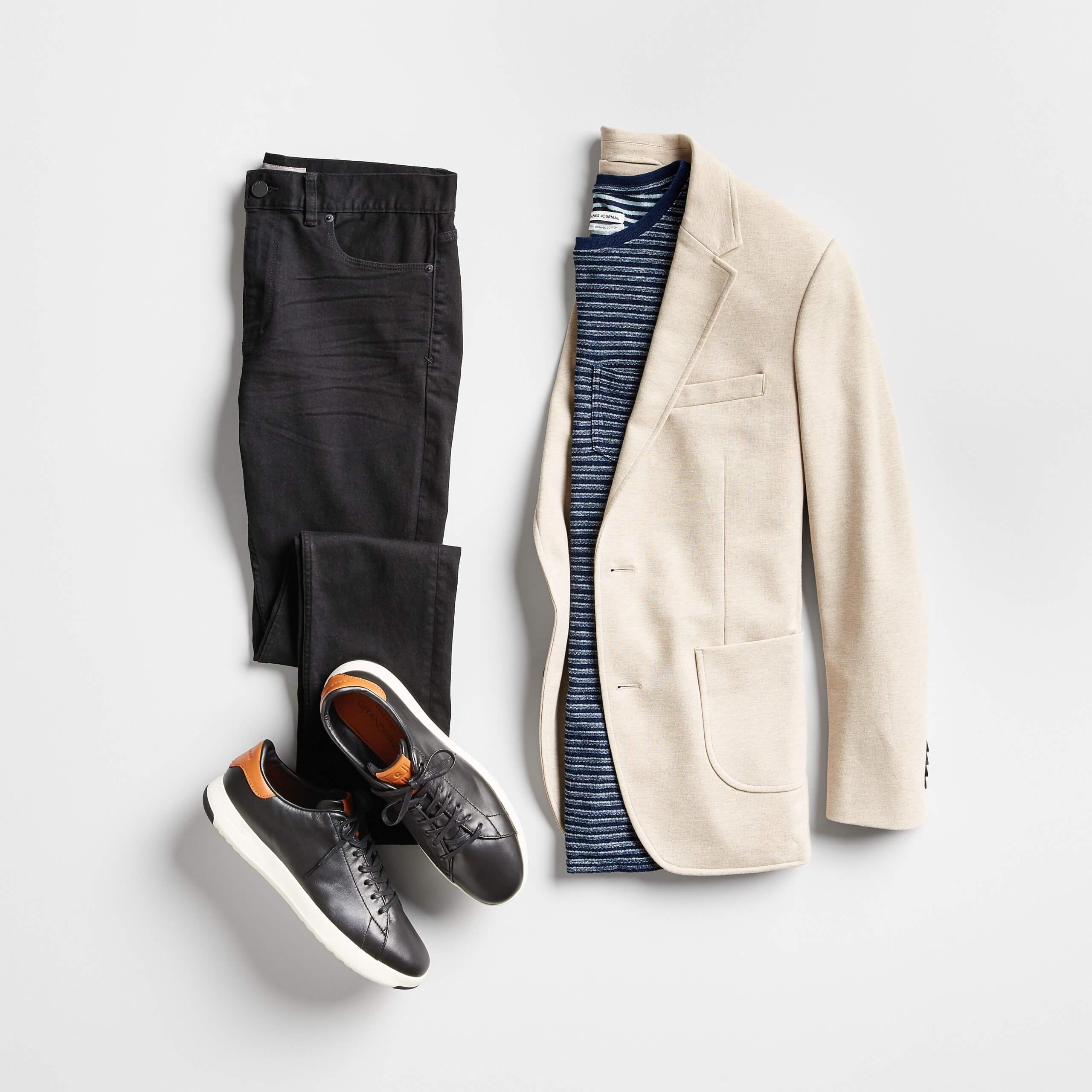 Stitch Fix Men’s outfit laydown featuring a beige blazer over a navy striped tee, next to black skinny jeans and black leather sneakers. 