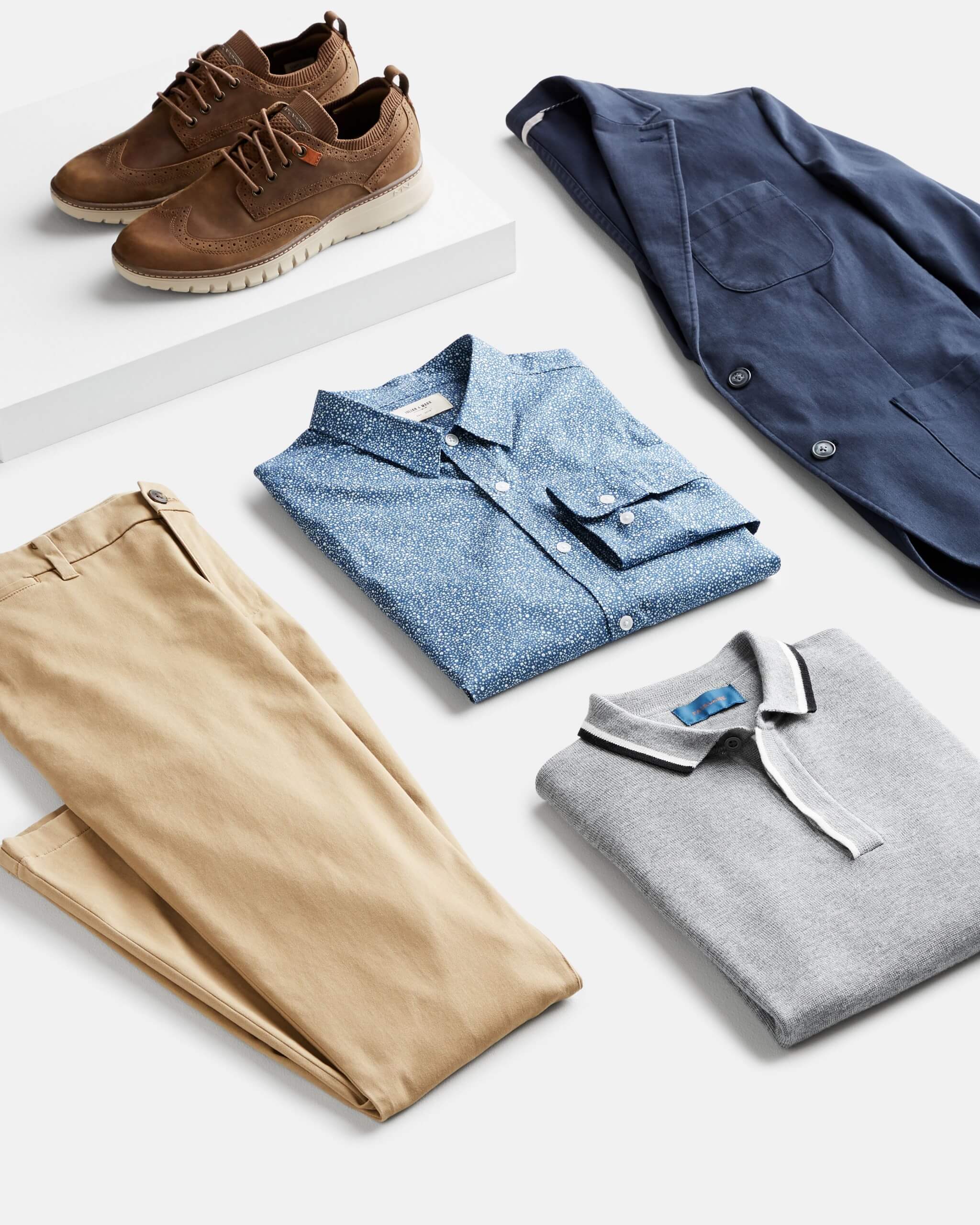 Stitch Fix Men’s outfit laydown featuring khaki pants, grey polo, chambray button-up, navy blazer and brown oxford shoes.