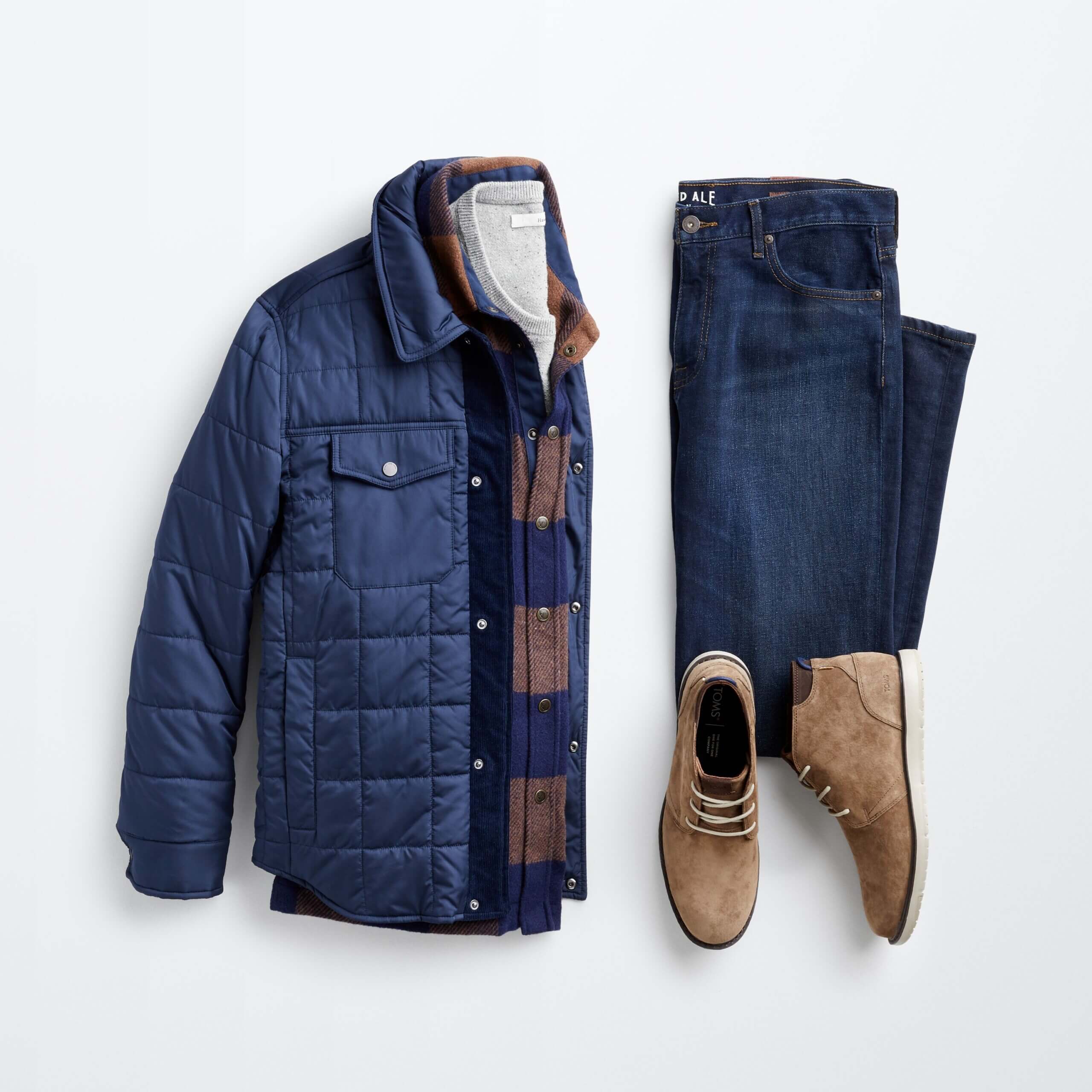 Stitch Fix men's outfit laydown featuring blue denim, grey t-shirt, plaid flannel button-up, navy puffer jacket and brown chukkas.