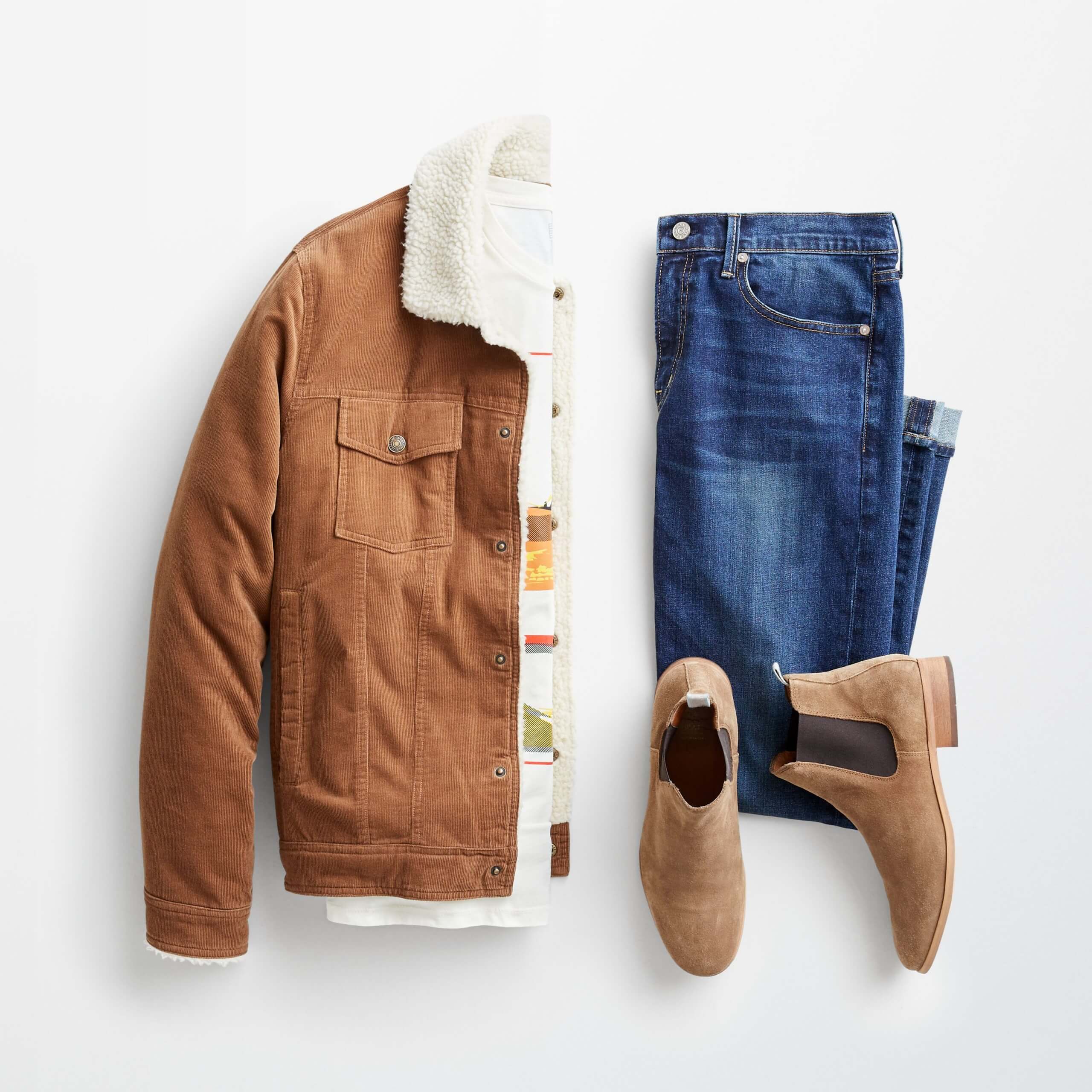 Stitch Fix Men’s outfit laydown featuring a brown corduroy jacket with sherpa lining over a graphic t-shirt, next to folded blue jeans and brown chelsea boots. 