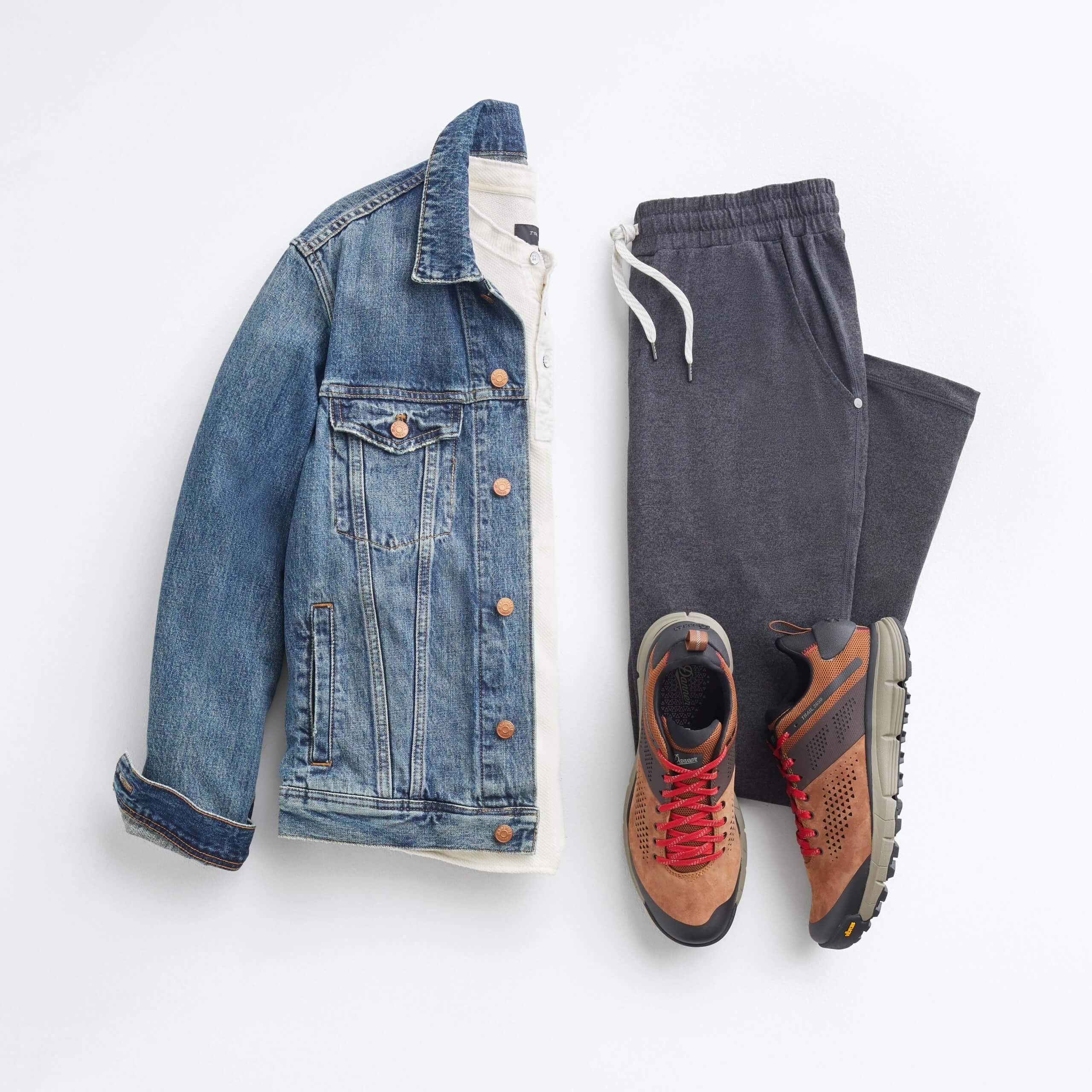 Stitch Fix Men’s outfit laydown featuring blue jean jacket over white henley, grey joggers and brown suede sneakers.