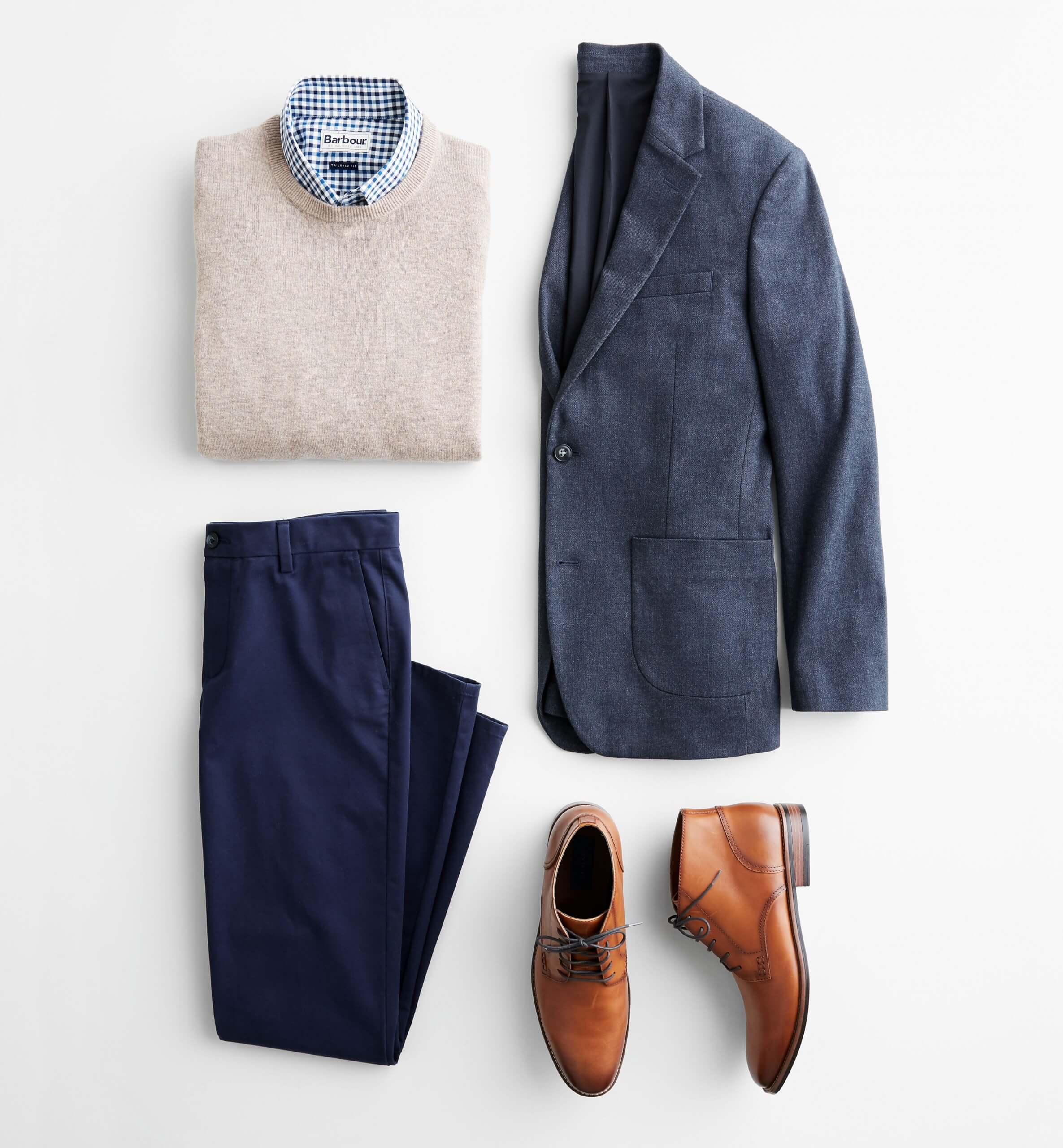 Stitch Fix Men's outfit laydown featuring navy blazer, cream crewneck sweater over blue collared shirt, navy trousers and brown leather chukkas. 