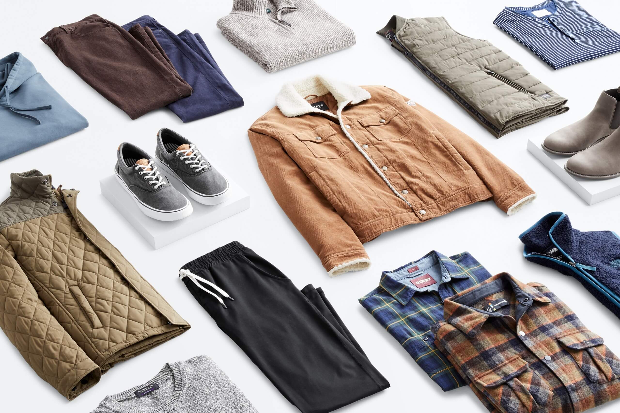 Stitch Fix Men’s outfit laydown featuring a blue hoodie, brown pants, navy pants, grey quarter zip sweater, olive quilted jacket, grey sneakers, brown trucker jacket with sherpa collar, olive quilted vest, blue henley, grey crew neck tee, black joggers, plaid button downs in rusted orange and navy colors and navy blue vest. 