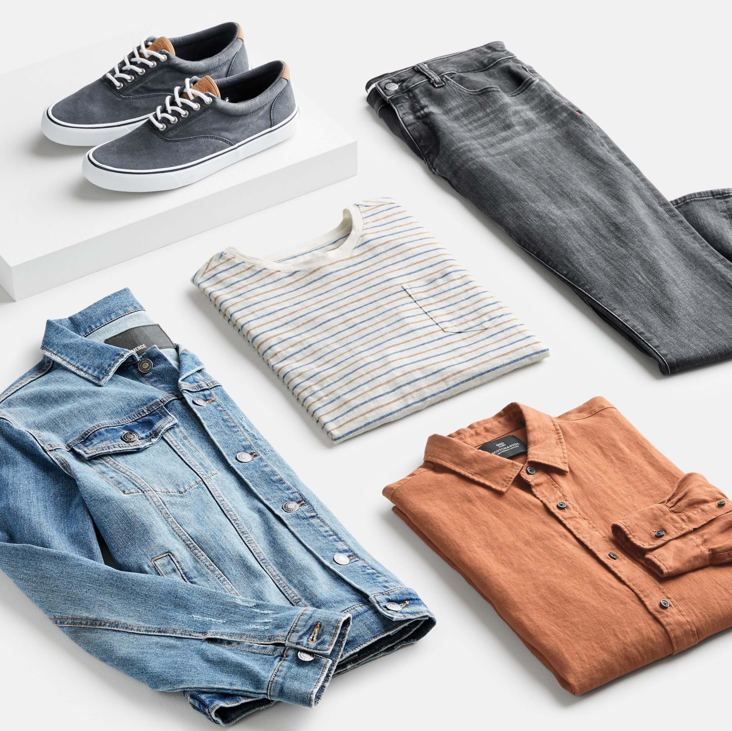 Stitch Fix Men’s outfit laydown featuring grey lace-up sneakers on a white block, next to a denim jacket, grey, blue and orange striped crew neck t-shirt, orange button-down shirt and grey jeans. 