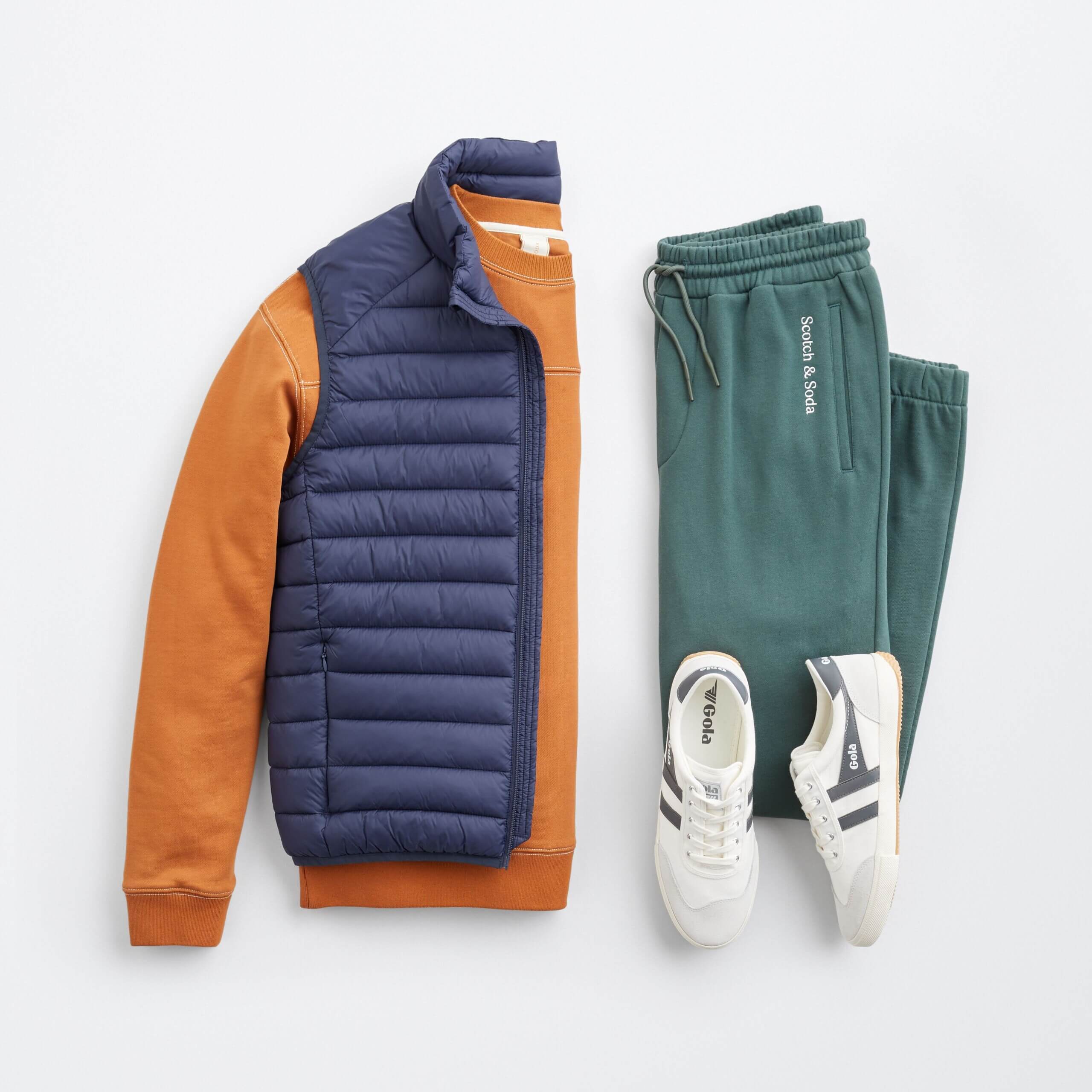 Stitch Fix men's outfit laydown featuring navy puffer vest over orange pullover, green joggers and white sneakers. 