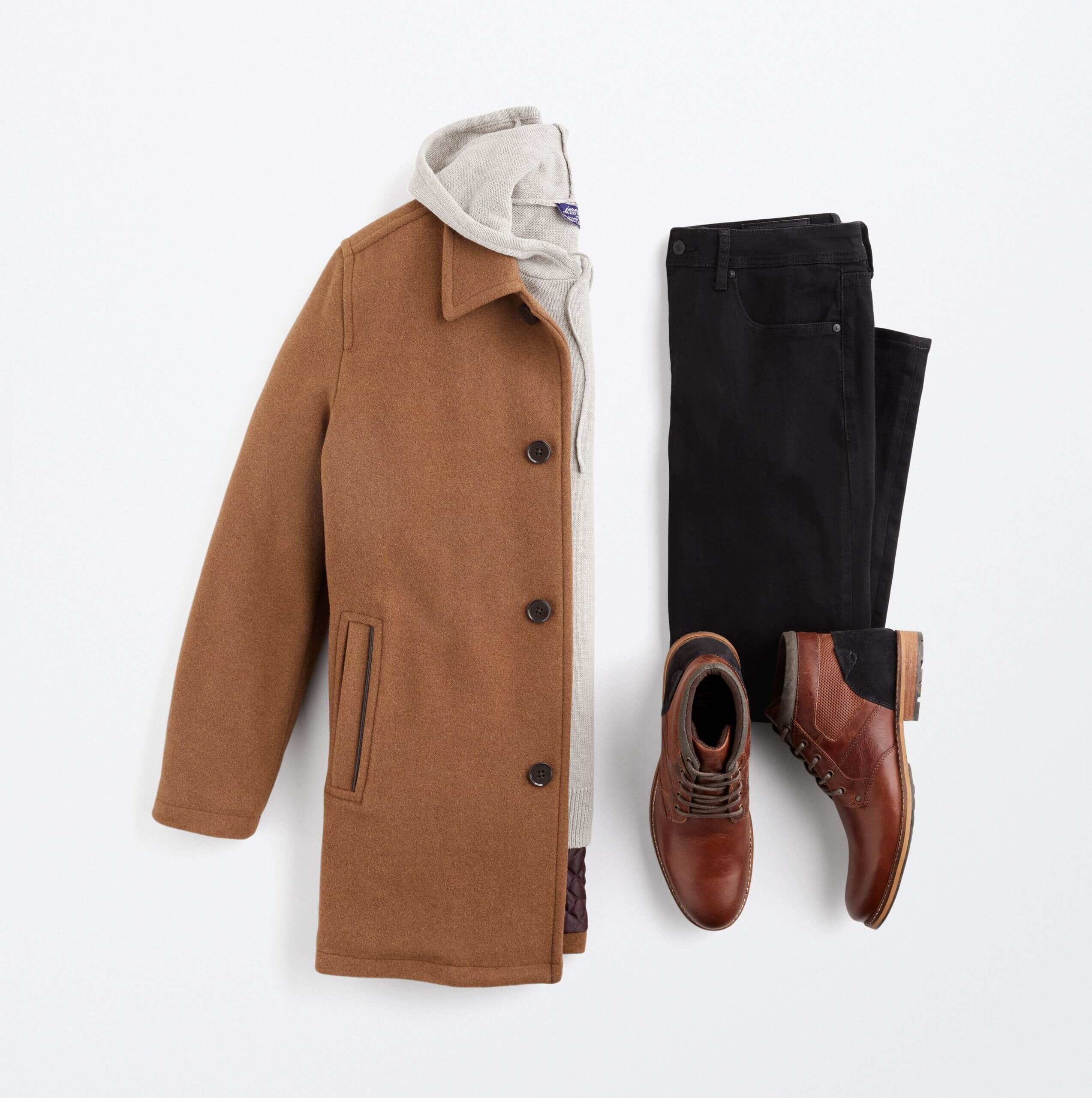 Stitch Fix men's outfit laydown featuring brown long coat over cream hoodie, black jeans and brown leather chukkas.