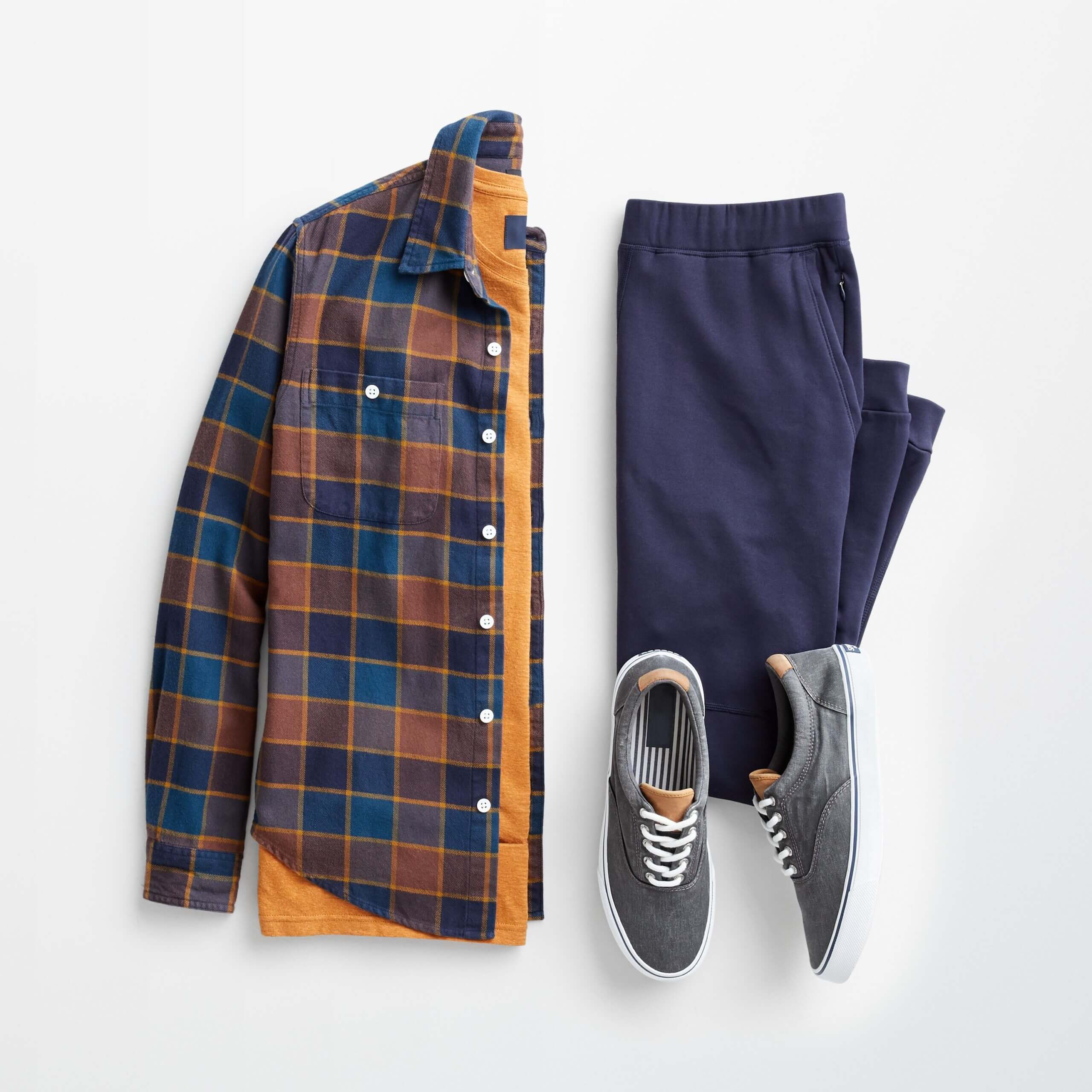 Stitch Fix men's outfit laydown featuring navy blue sweatpants, canvas sneakers and navy blue and mustard plaid flannel over a mustard tee. 