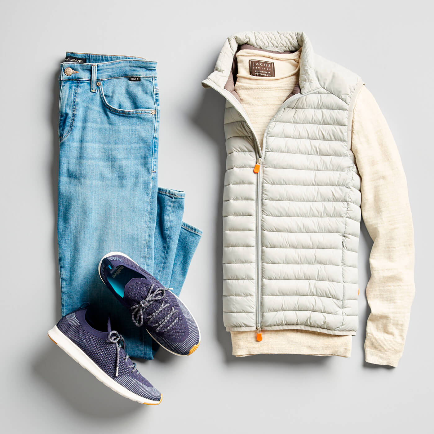 light wash jeans, blue sneakers, and light tan puffer vest