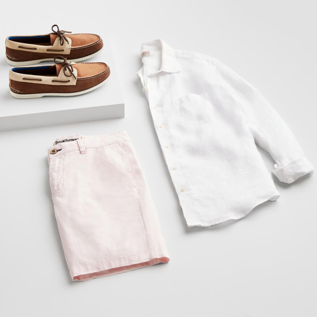 Stitch Fix Men’s Wedding outfit featuring light pink shorts, white linen button-down shirt and brown and tan boat shoes.