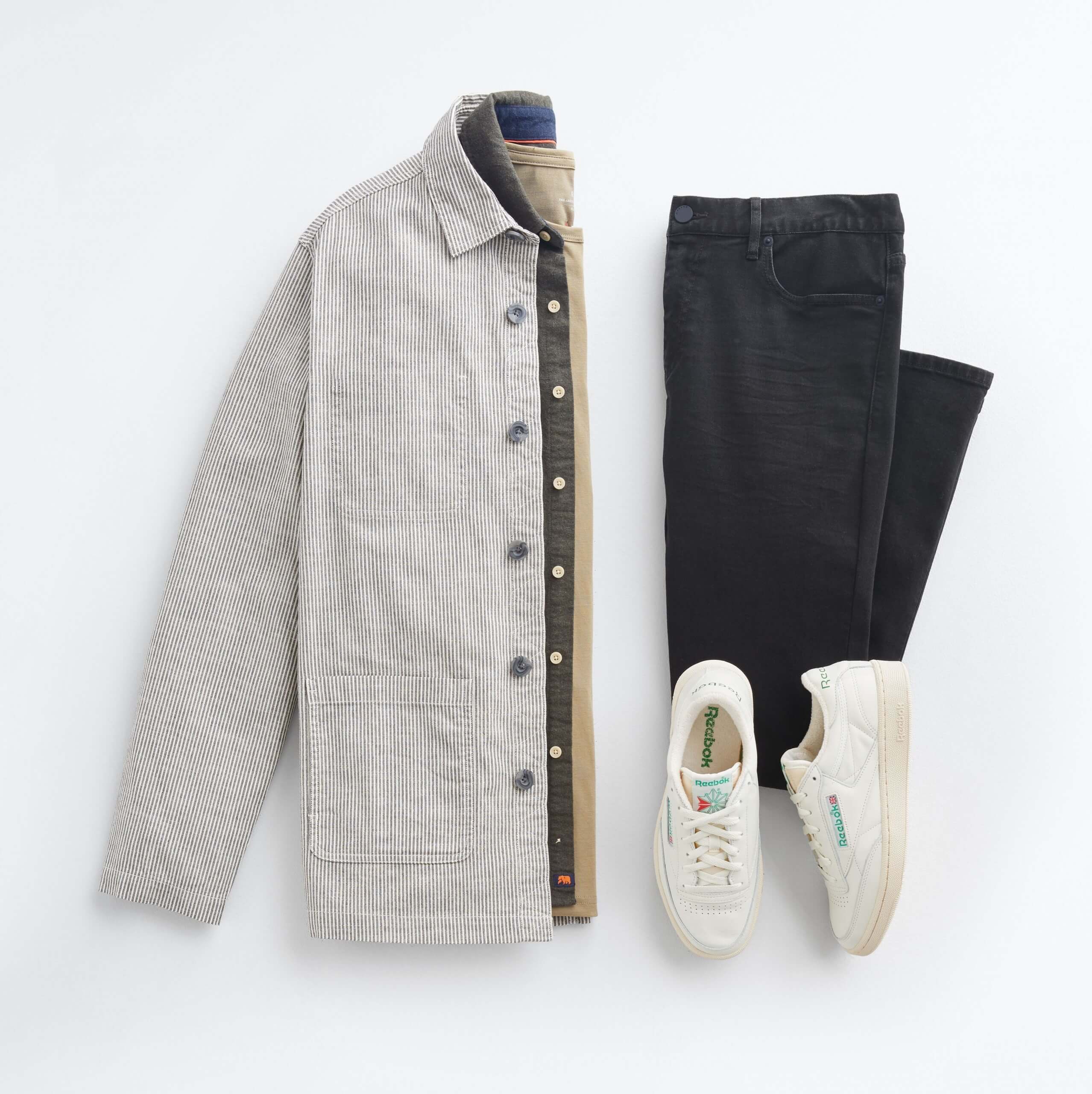 Stitch Fix Men's outfit laydown featuring beige chore jacket over green oxford shirt and olive crewneck t-shirt, next to black jeans and white sneakers.