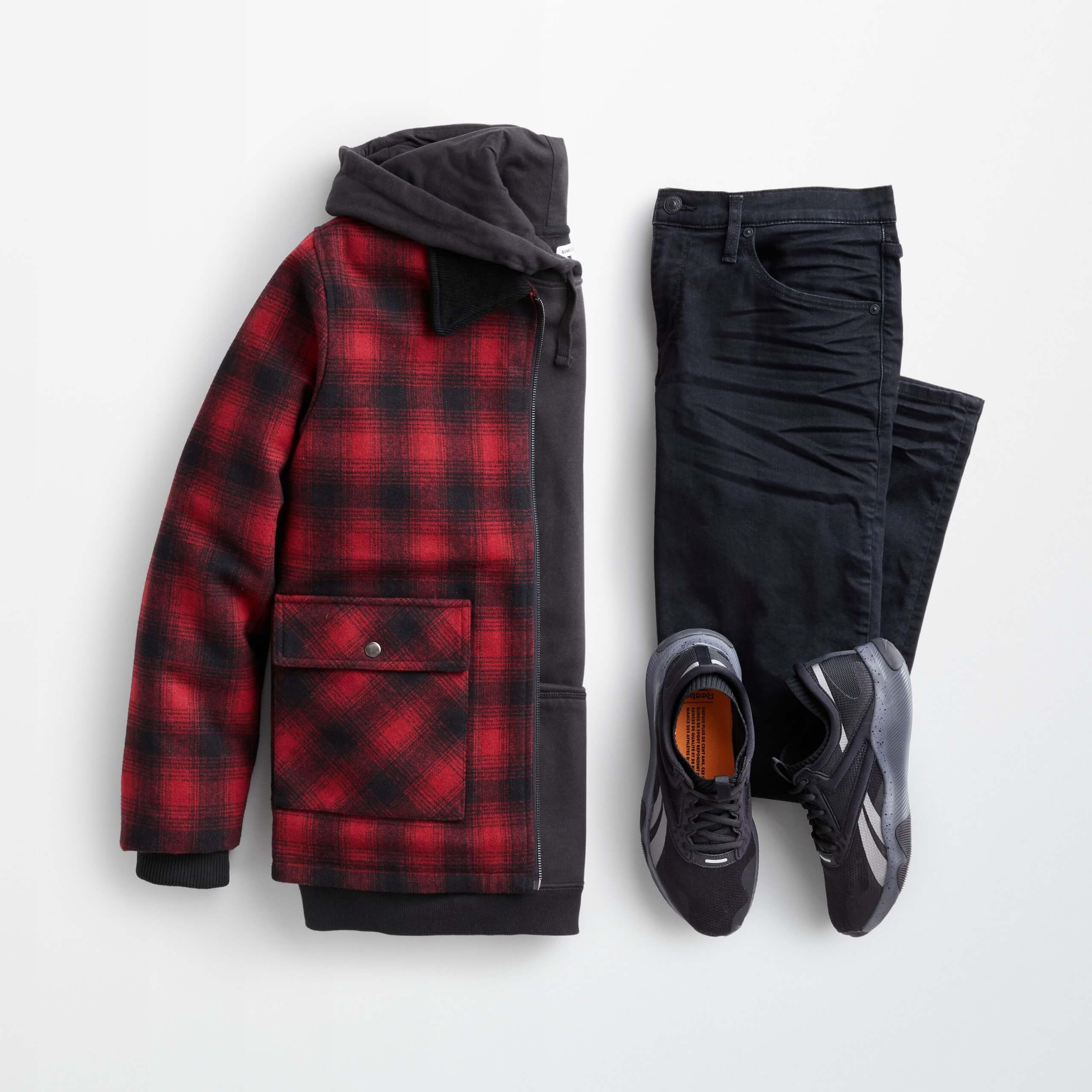 Stitch Fix Men's outfit laydown featuring a red and black plaid trucker jacket over a black hoodie, next to black jeans and black sneakers.