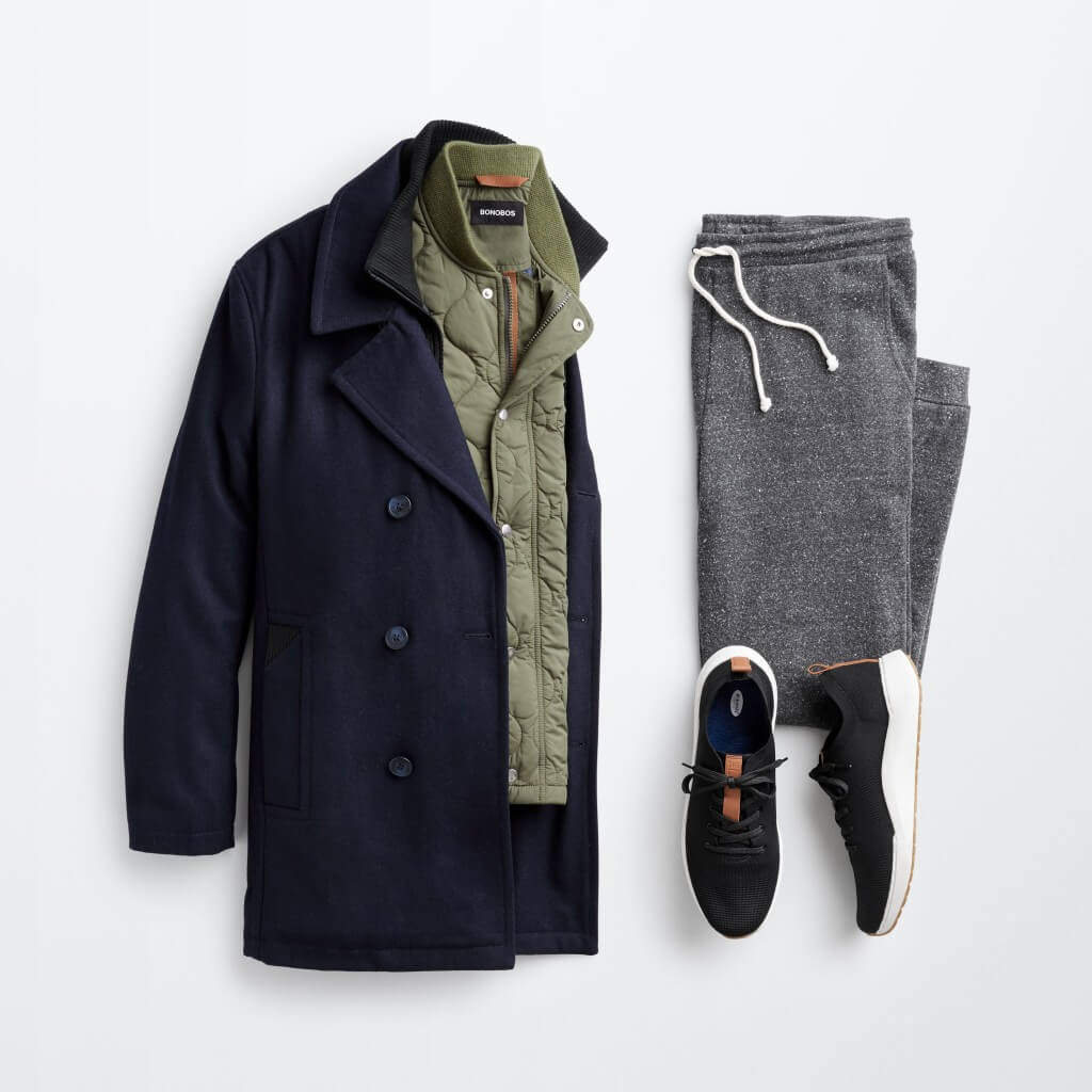 Stitch Fix men’s outfit laydown featuring a black peacoat, olive green jacket, grey joggers and black sneakers.