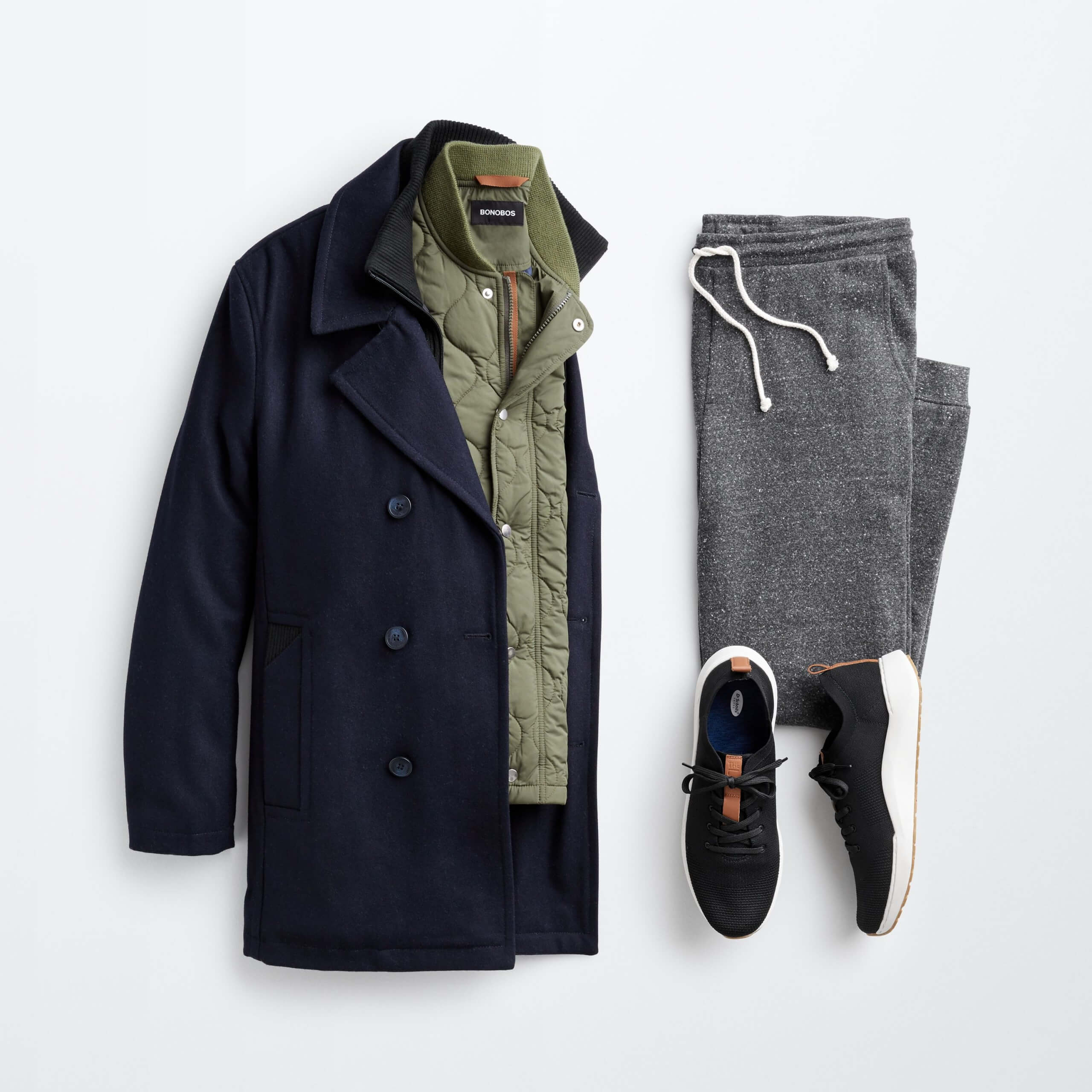 Stitch Fix men’s outfit laydown featuring a black peacoat, olive green jacket, grey joggers and black sneakers.