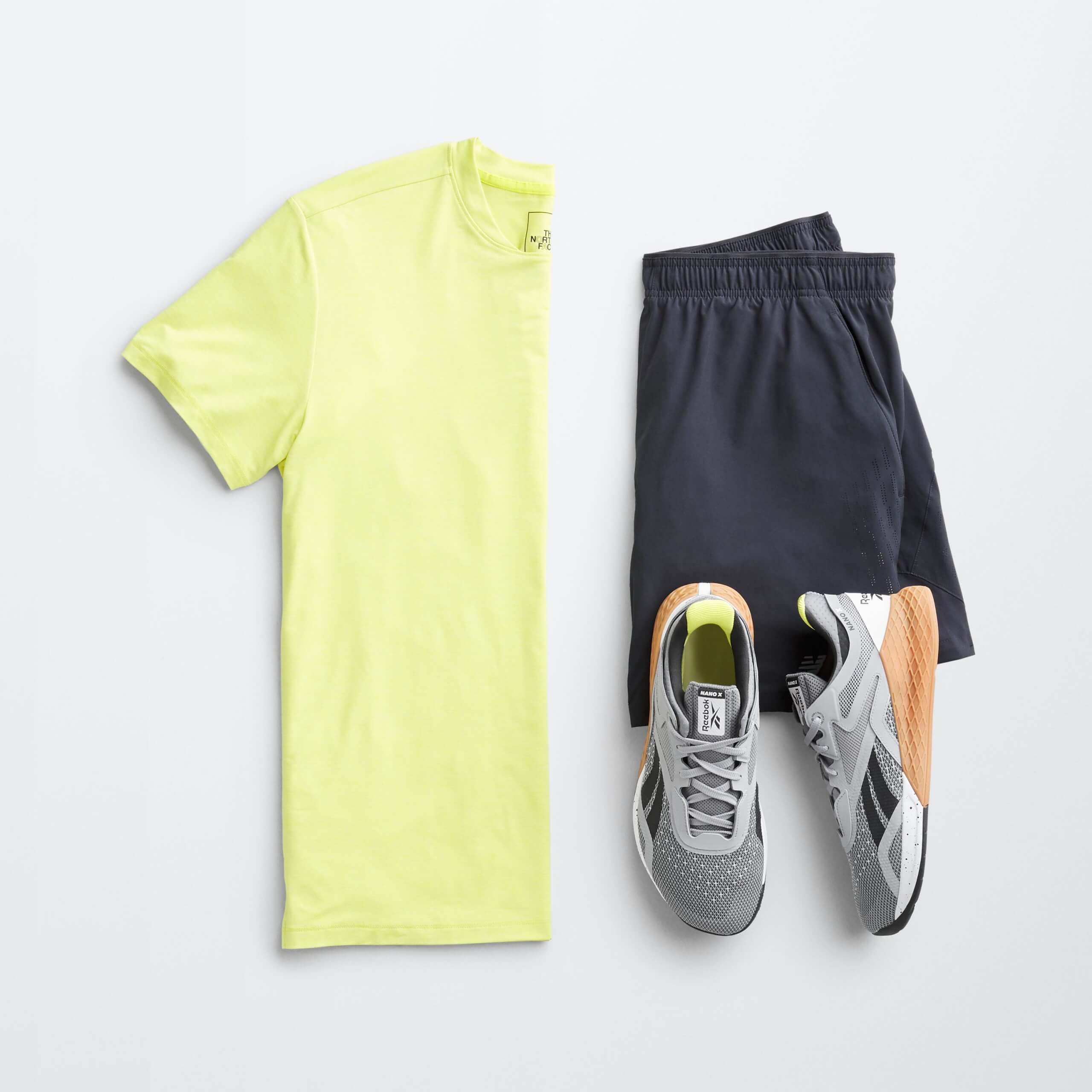 Stitch Fix men’s outfit laydown featuring neon yellow T-shirt, black elastic shorts and multi-colored sneakers.