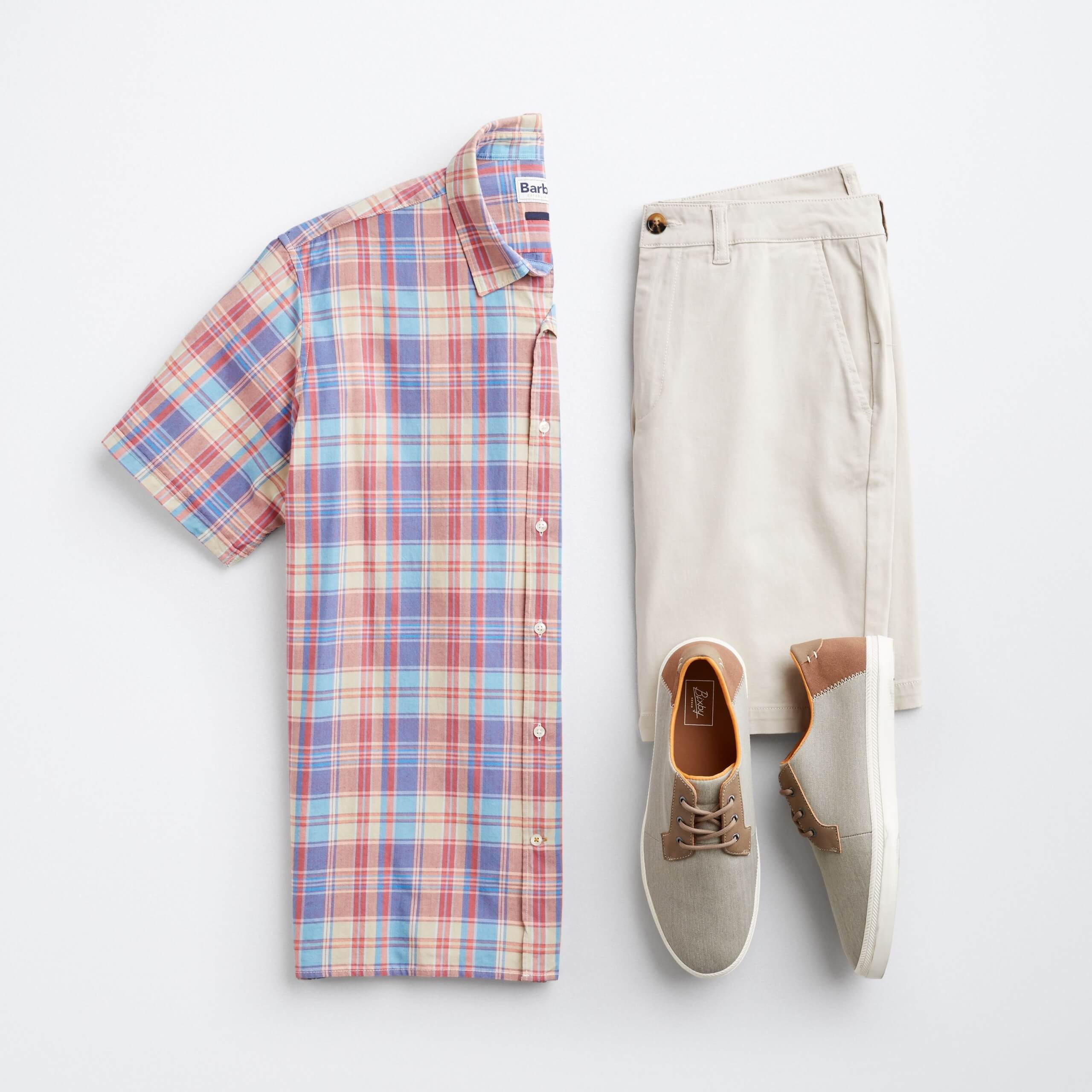 Stitch Fix men’s laydown featuring plaid short-sleeved button-down shirt, tan trouser shorts, and grey and brown sneakers.