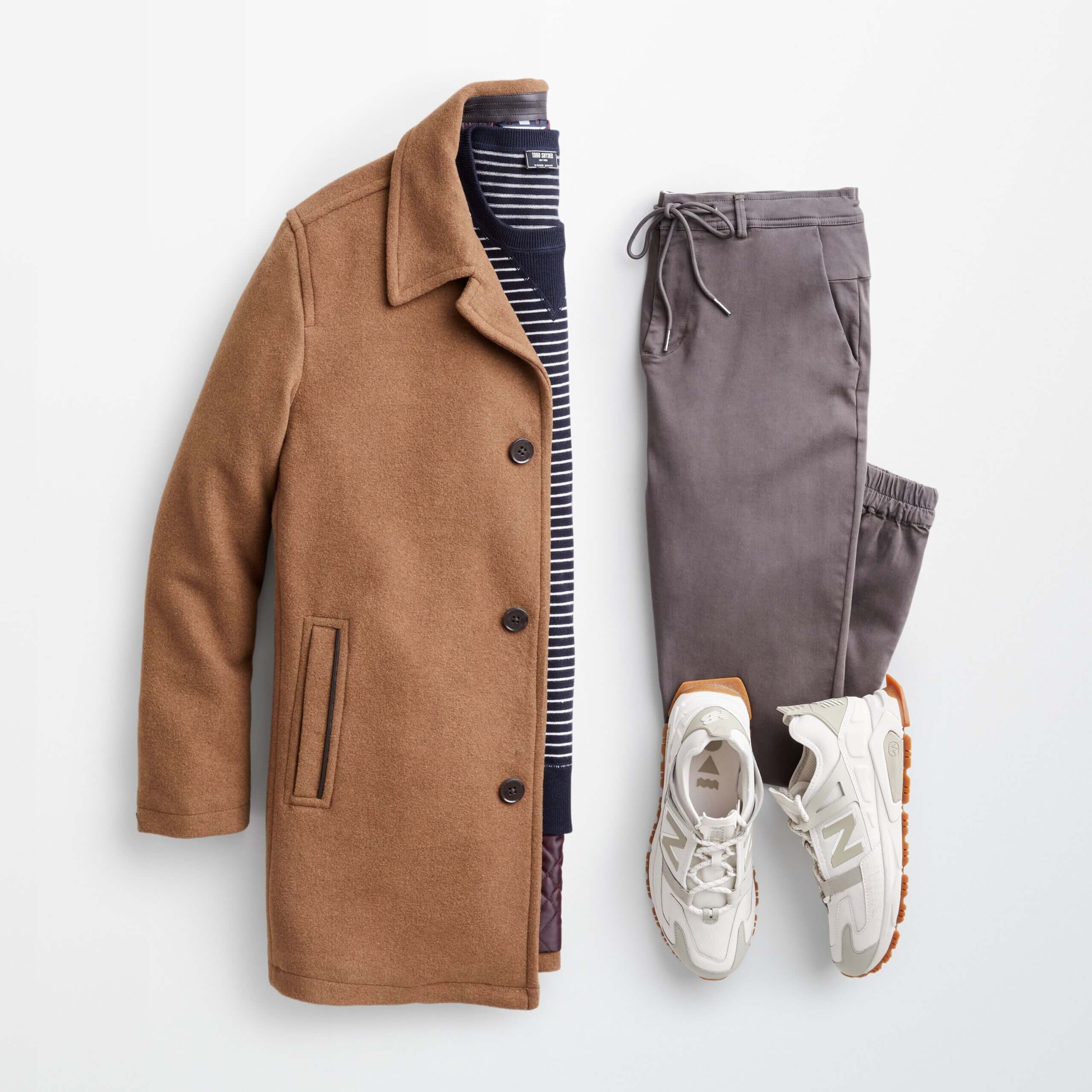 Stitch Fix men’s back to the office outfit with navy striped sweater, grey chino joggers, white lace-up sneakers and brown wool coat.