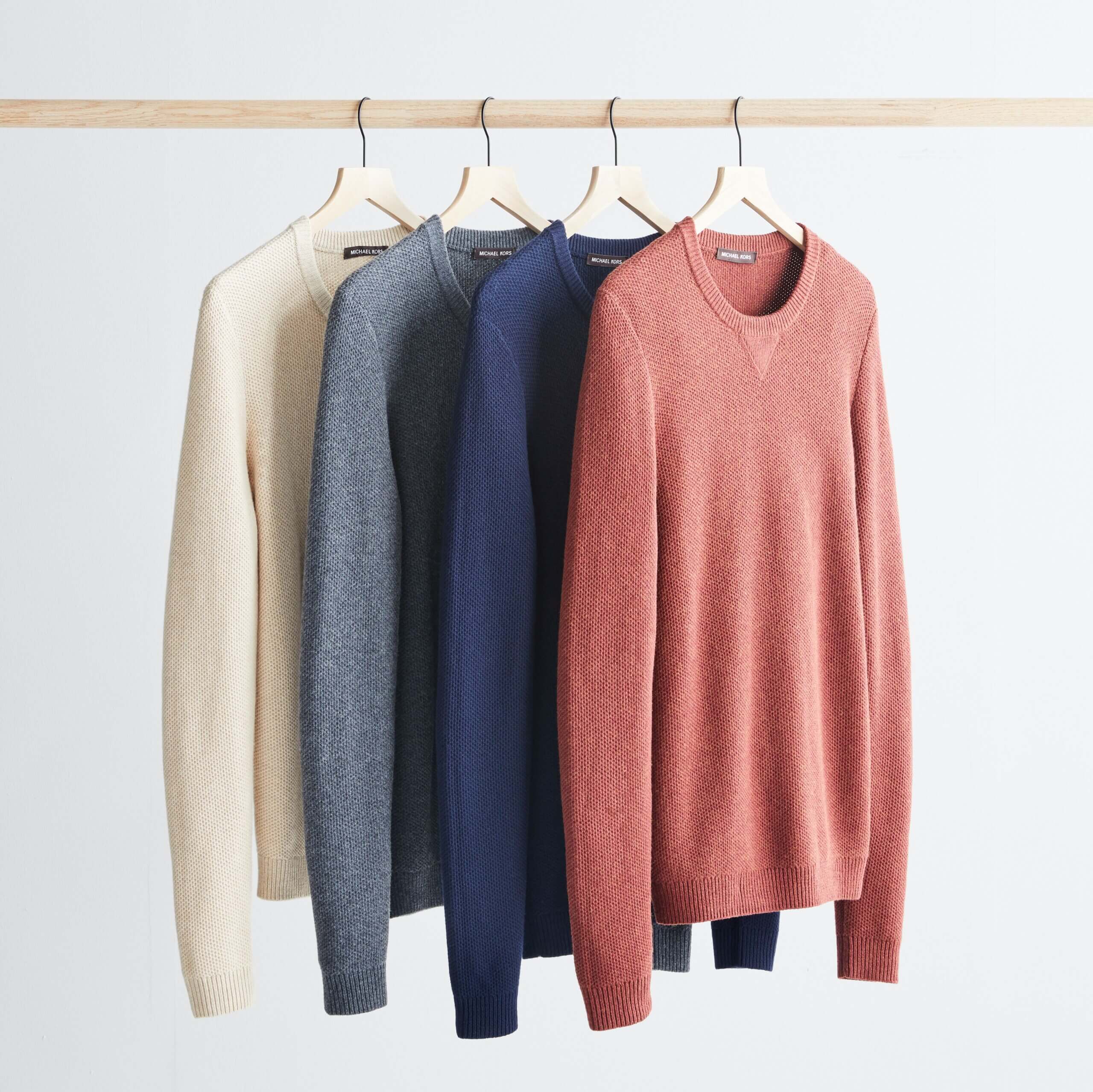 Stitch Fix men’s red, navy, blue and white crewneck sweaters hanging from rack.