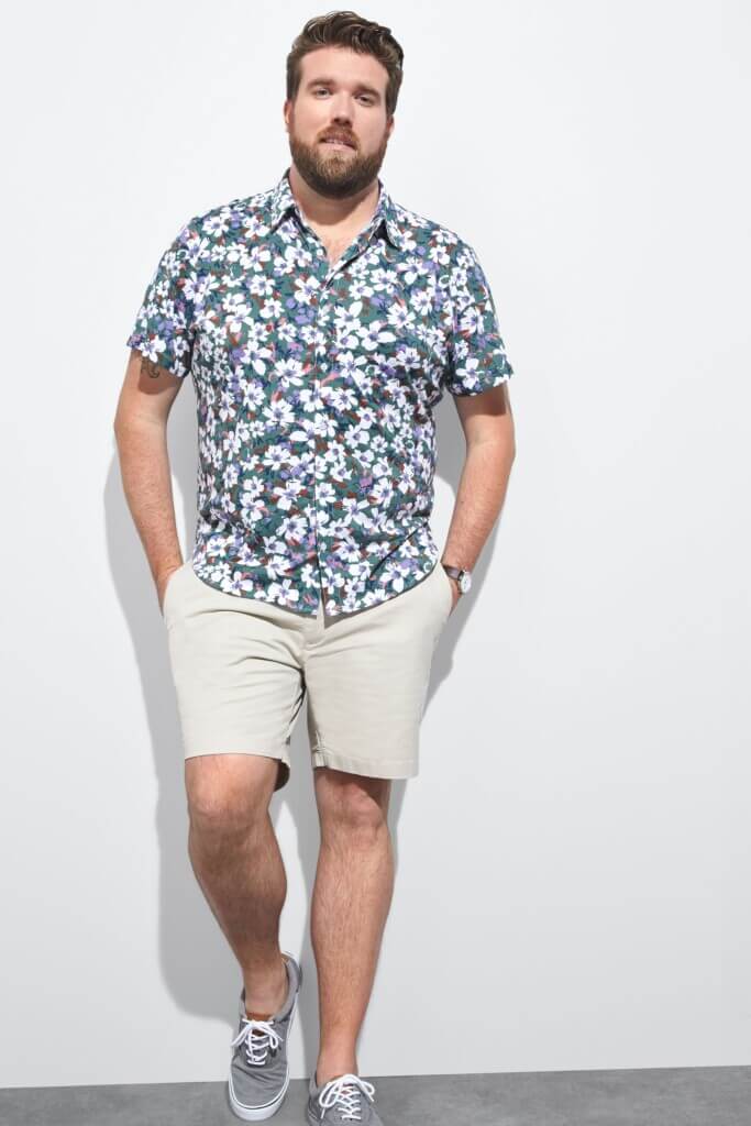 Stitch Fix model wearing men’s resort wear floral button-up shirt, beige shorts, grey sneakers and wristwatch.