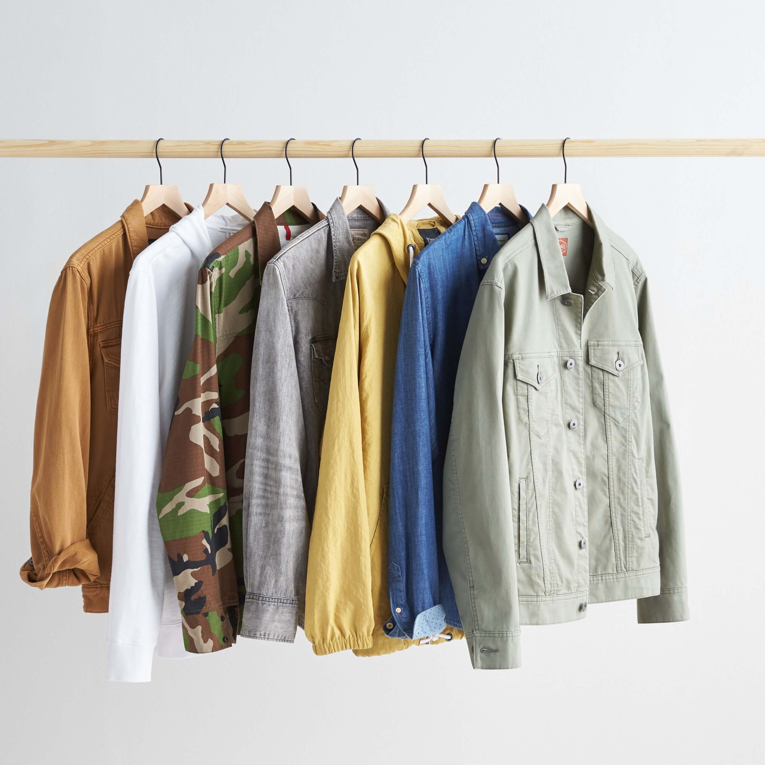 Stitch Fix men’s outerwear collection featuring denim jackets, hoodies, camo jacket and denim button-up shirt hanging on a rack.