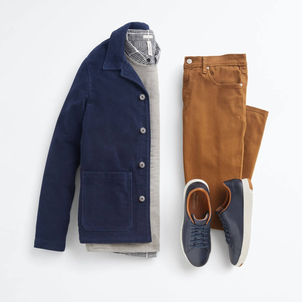 Stitch Fix men's New Year's Eve outfit featuring gray sweater over black and white plaid button-down shirt, black jeans and black boots.