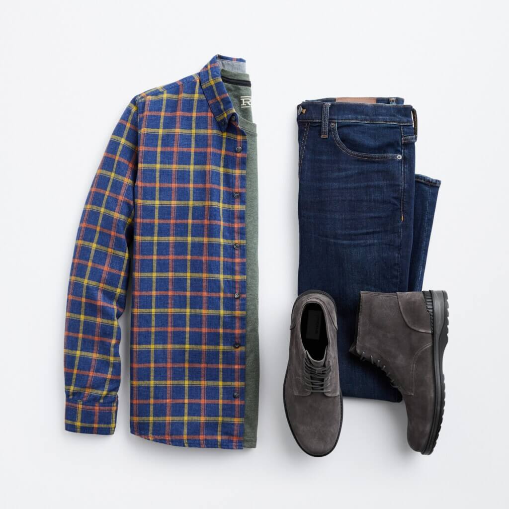 Stitch Fix men’s outfit for shorter men featuring blue, yellow and red plaid button-down shirt, green shirt, dark denim jeans and dark grey boots.