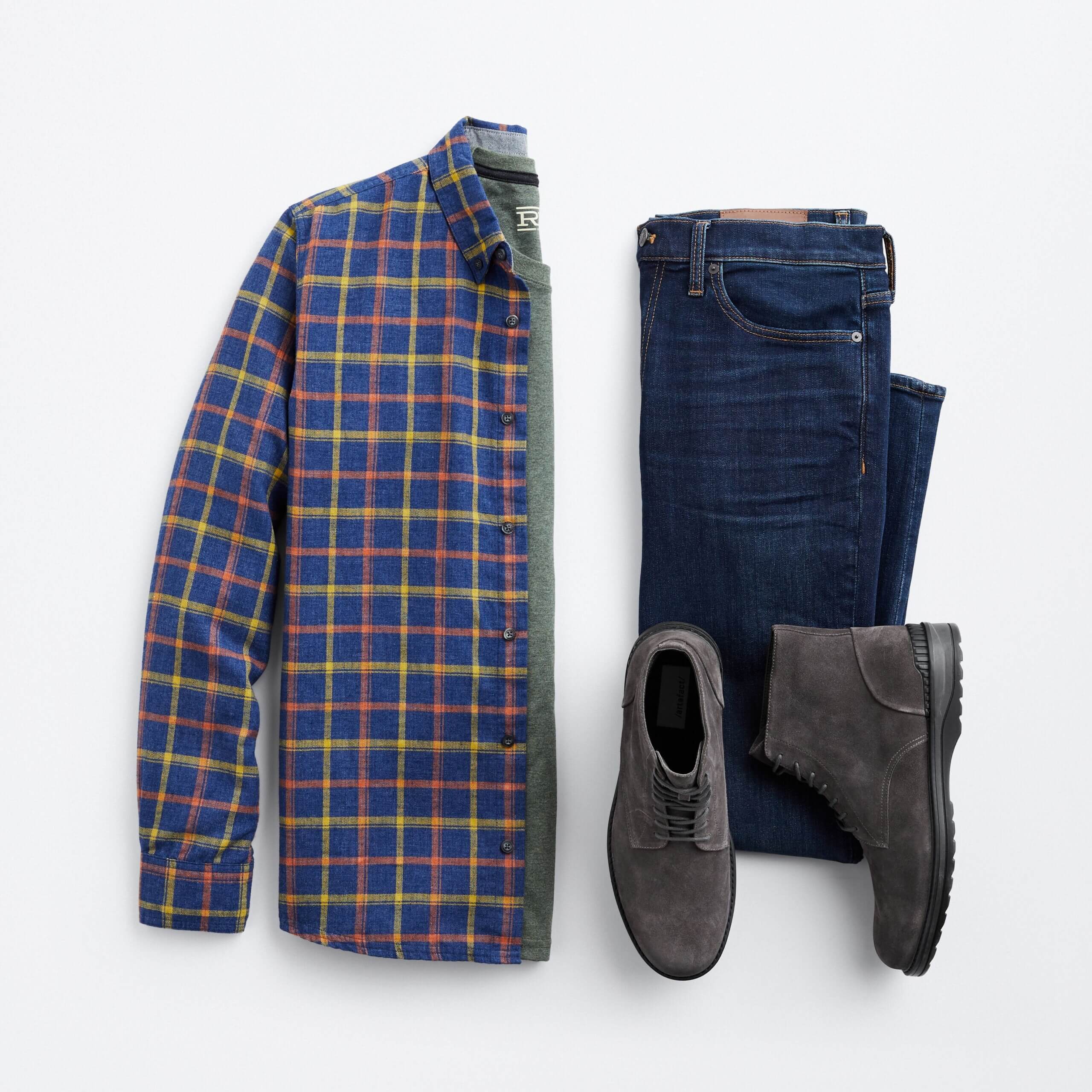 Stitch Fix men’s outfit for shorter men featuring blue, yellow and red plaid button-down shirt, green shirt, dark denim jeans and dark grey boots.