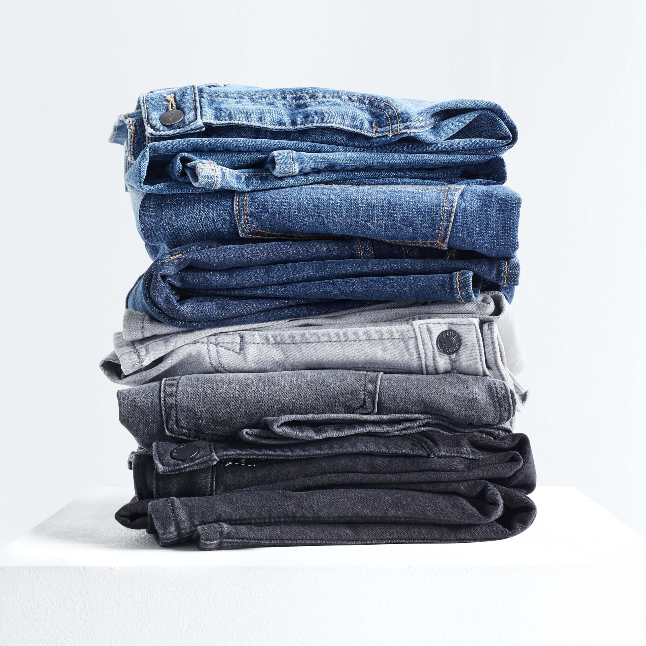 Stitch Fix men’s stack of light blue, blue, grey and black jeans.