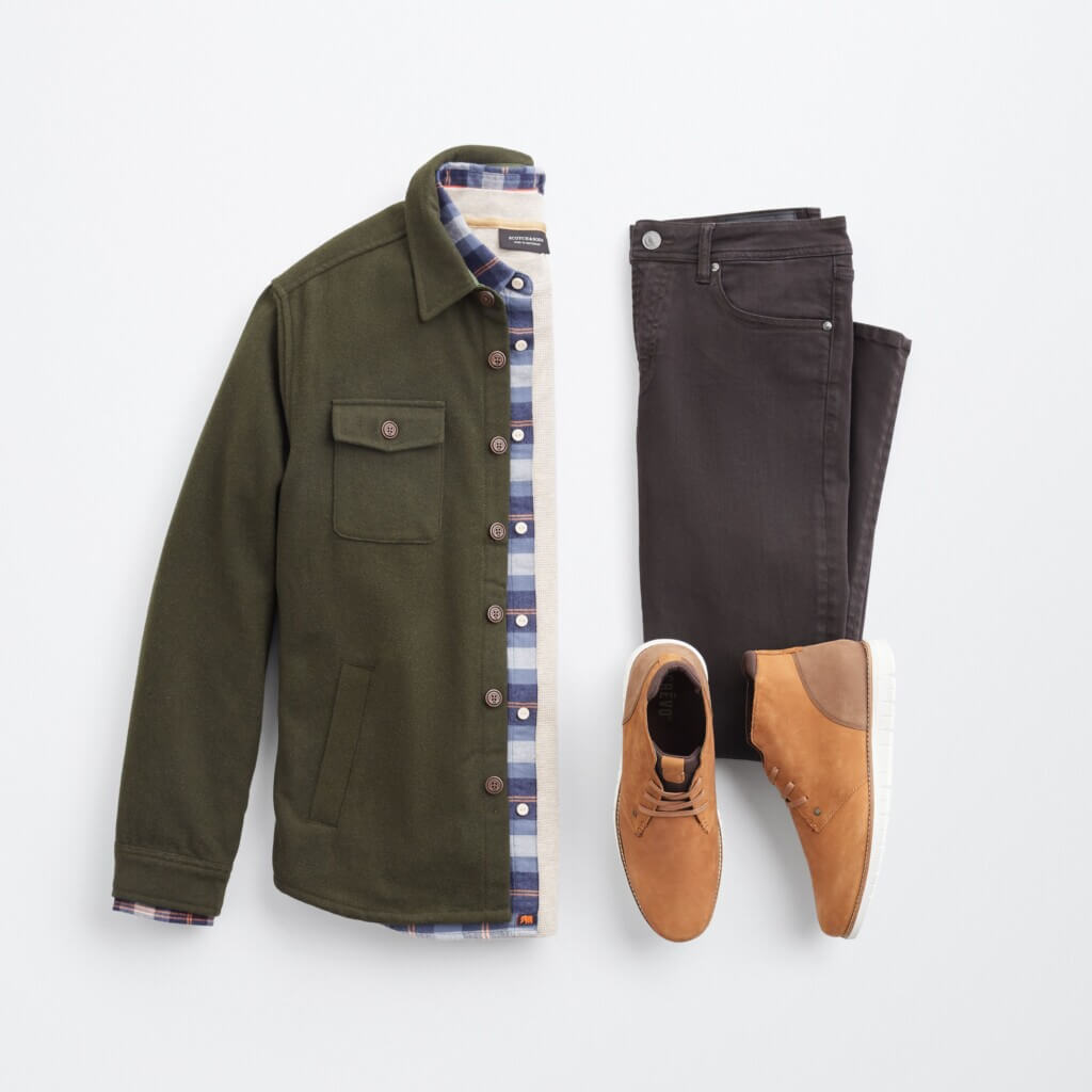 Stitch Fix men’s big and tall outfit with beige shirt, plaid button-down shirt, olive shacket, black jeans and brown chukkas.