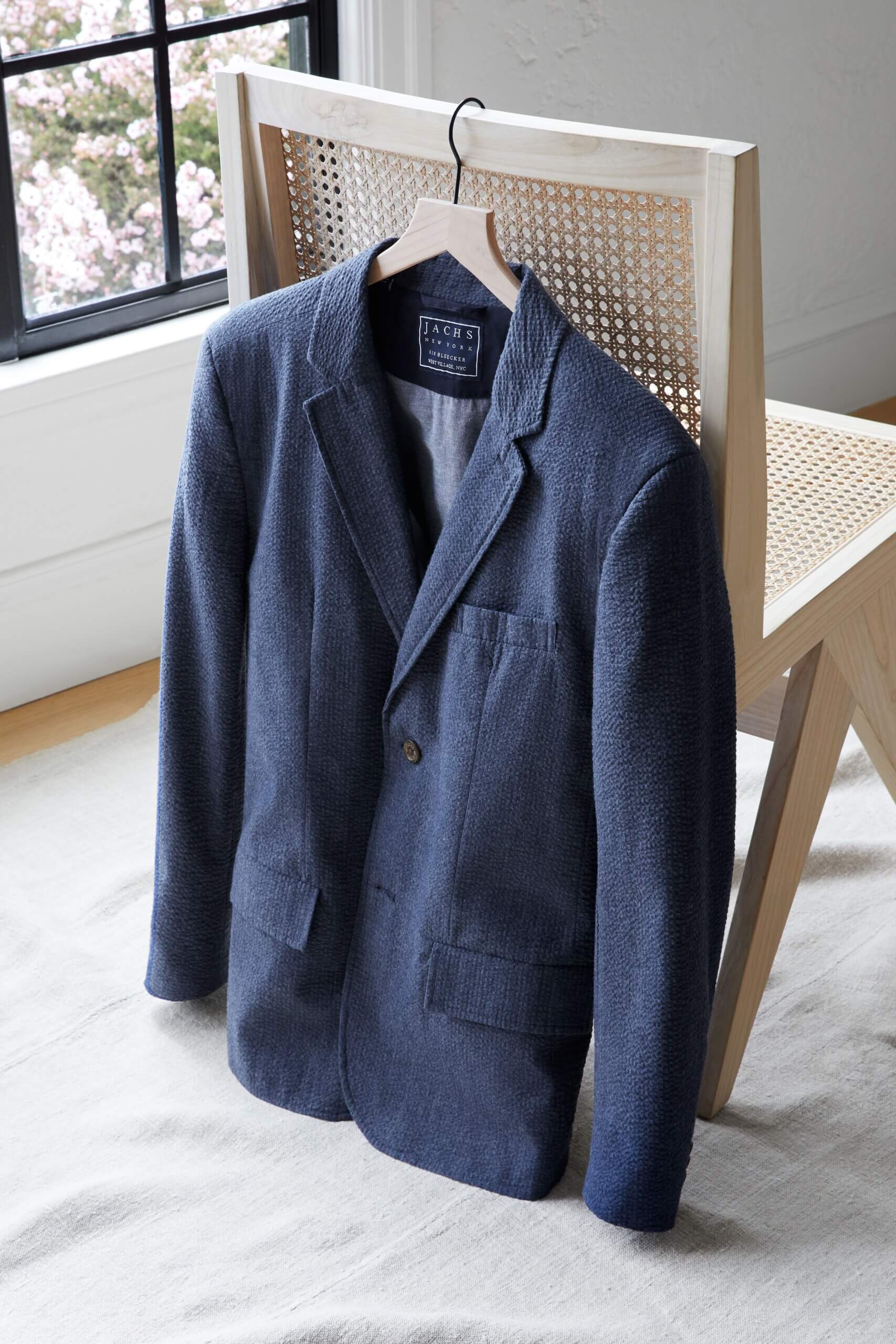 Stitch Fix men's navy blue blazer hanging from a hanger off a chair.