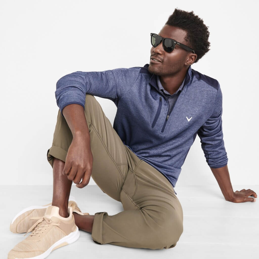Stitch Fix men’s golf attire outfit on model featuring olive chinos, navy polo, navy quarter-zip pullover, beige sneakers and sunglasses.
