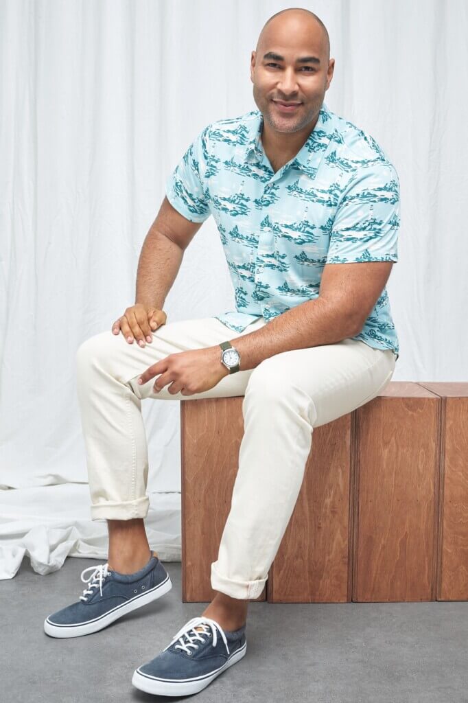 Stitch Fix model wearing beach wedding attire for men outfit featuring printed short sleeve button-down shirt, pants and sneakers.