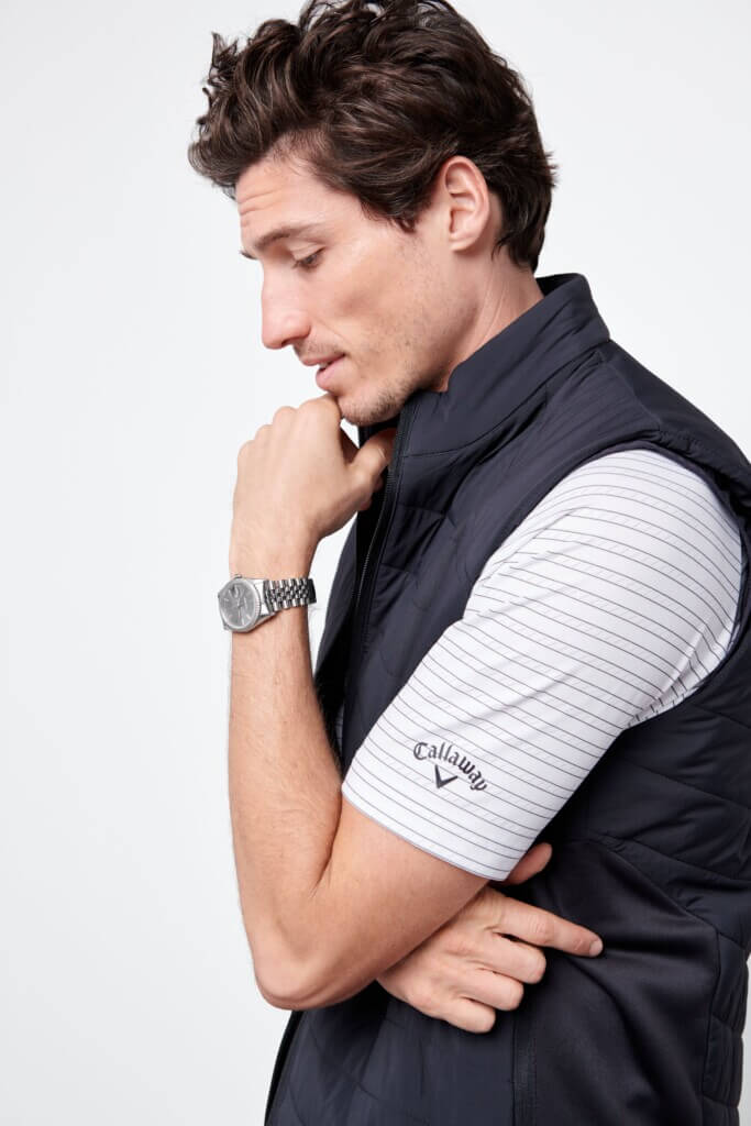 Stitch Fix men’s golf attire outfit on model featuring striped polo shirt, black puffer vest and silver watch.