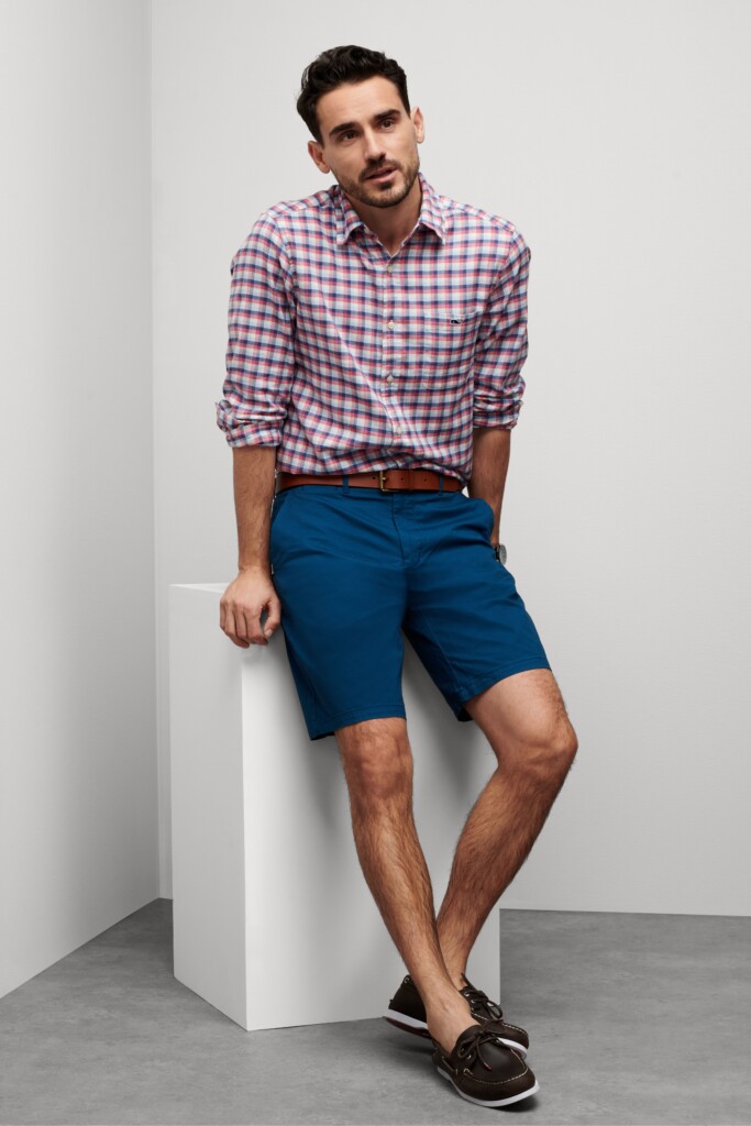 Stitch Fix model wearing preppy style men’s outfit featuring red and white plaid shirt, navy shorts, brown belt and loafers.
