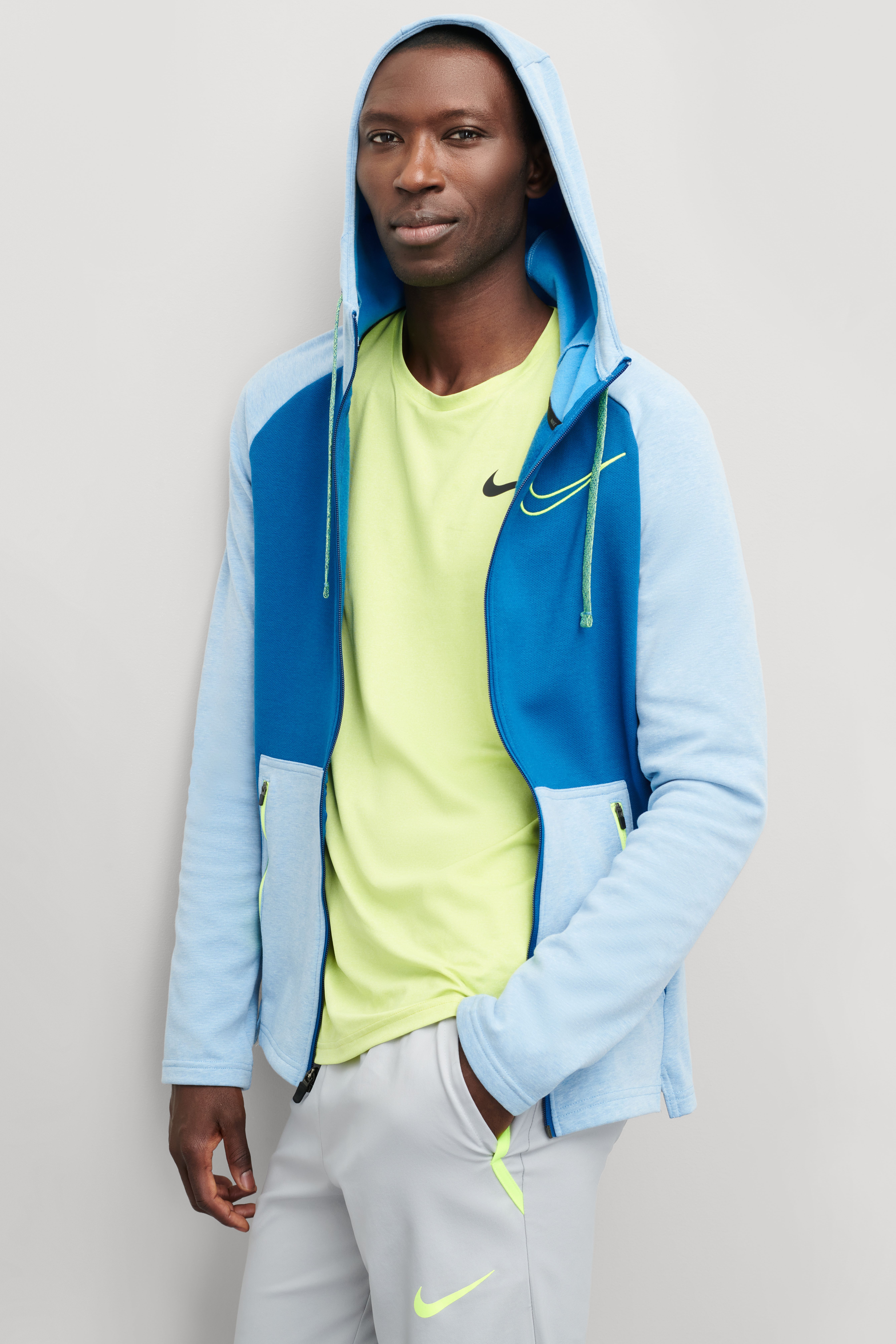 Stitch Fix model wearing Y2K fashion for men outfit with neon green tee, blue jacket, grey joggers with brand logo.