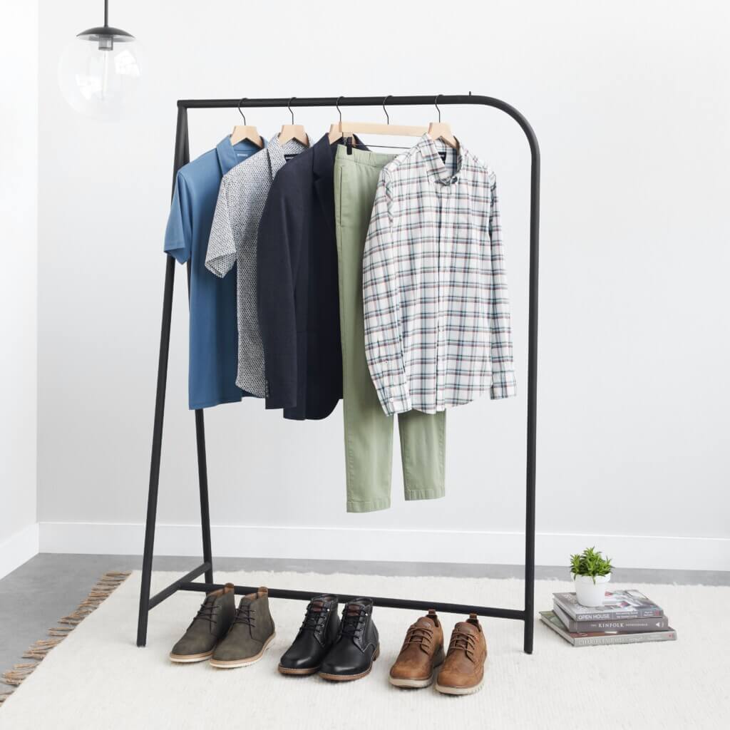 Stitch Fix men’s wedding attire outfit with shirts, pants and jackets hanging on rack next to various dress shoes and decor.