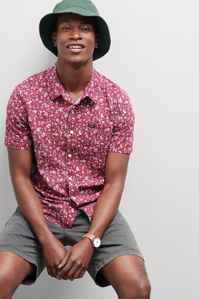 Stitch Fix men’s model wearing Y2K fashion for men outfit with grey shorts, red floral print shirt and green bucket hat.