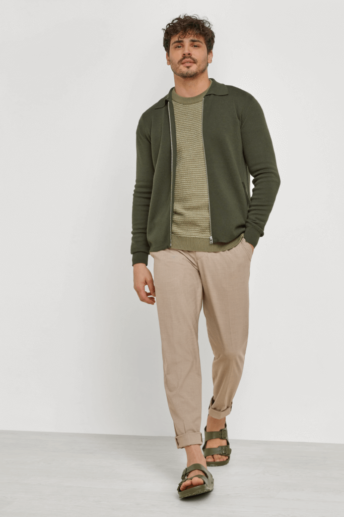 Stitch Fix Men’s model wearing a cardigan outfit with an olive shirt, olive zip-up cardigan, tan cuffed pants and olive sandals.
