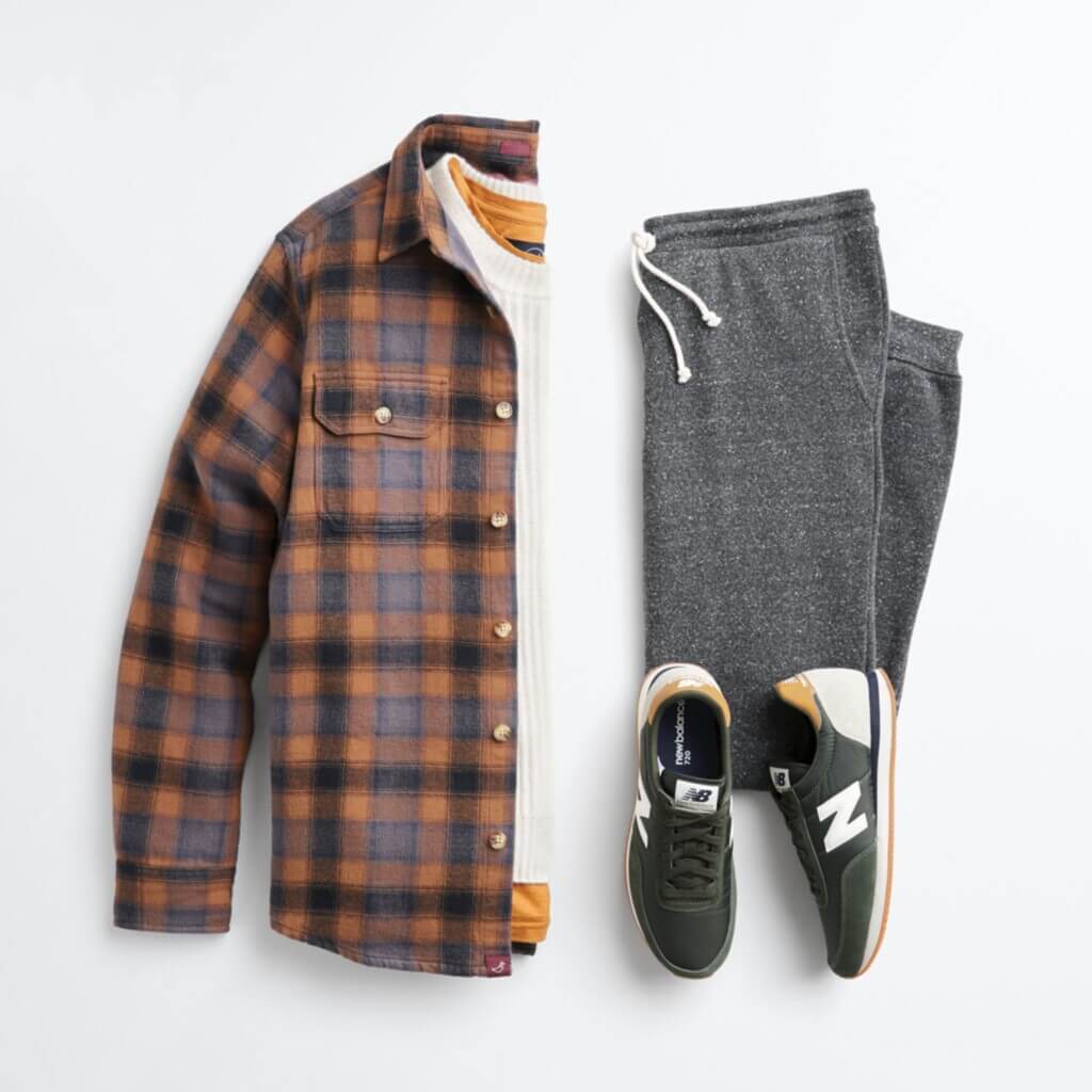 Stitch Fix Men’s cabincore outfit laydown with white shirt, plaid button-up shirt, grey joggers and black sneakers.