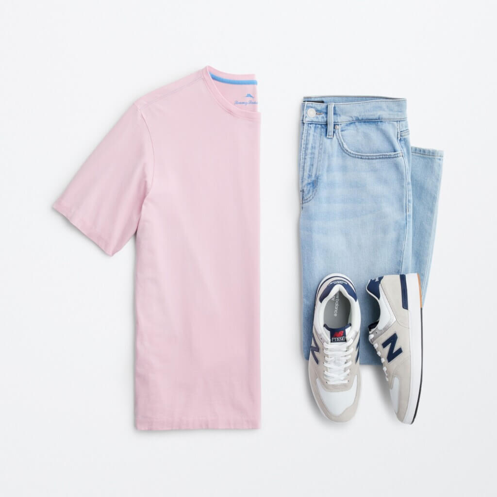 Top view of men’s summer clothes: pink tee, light wash jeans, and sneakers.