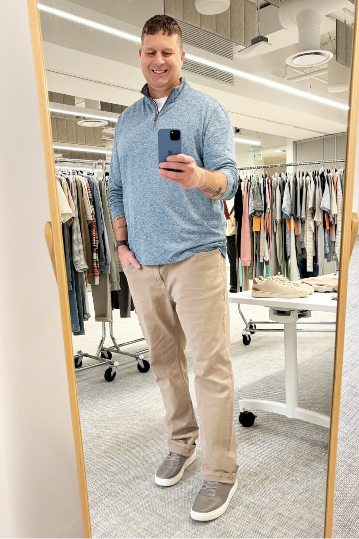 man taking selfie in mirror in big and tall outfit with khakis and quarter zip