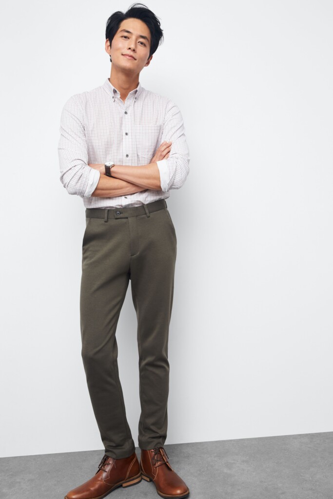 Stitch Fix model wearing men’s fall wedding attire outfit with grey pants, white long sleeved button-down, brown chukkas.