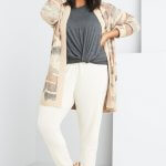 Stitch Fix model wearing plus-size clothing featuring grey knot front t-shirt, tan printed cardigan, cream joggers and slippers