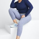 Stitch Fix model wearing plus-size clothing featuring navy long sleeve top, blue leggings and sneakers.